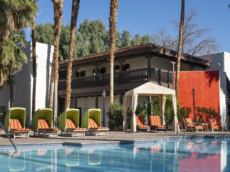 A pool with lounge chairs and a building