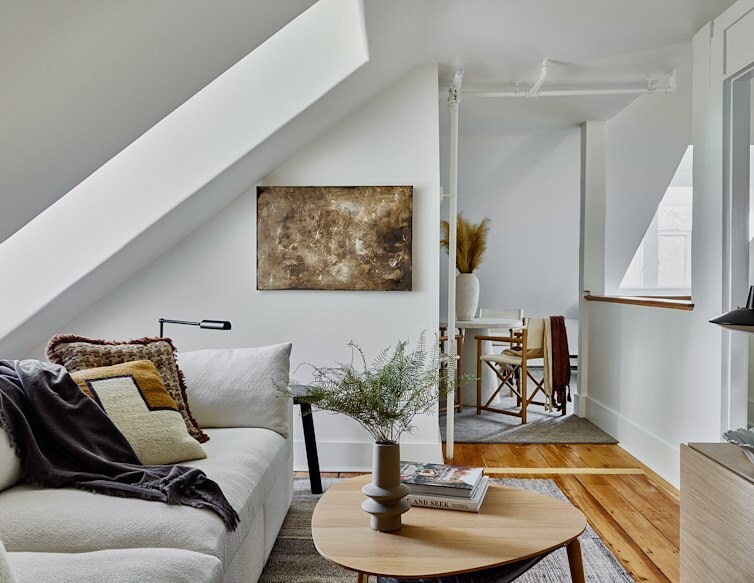 Bright hotel suite at AWOL Stowe with a white sofa, wood floors, modern furnishings, and a cozy dining nook.