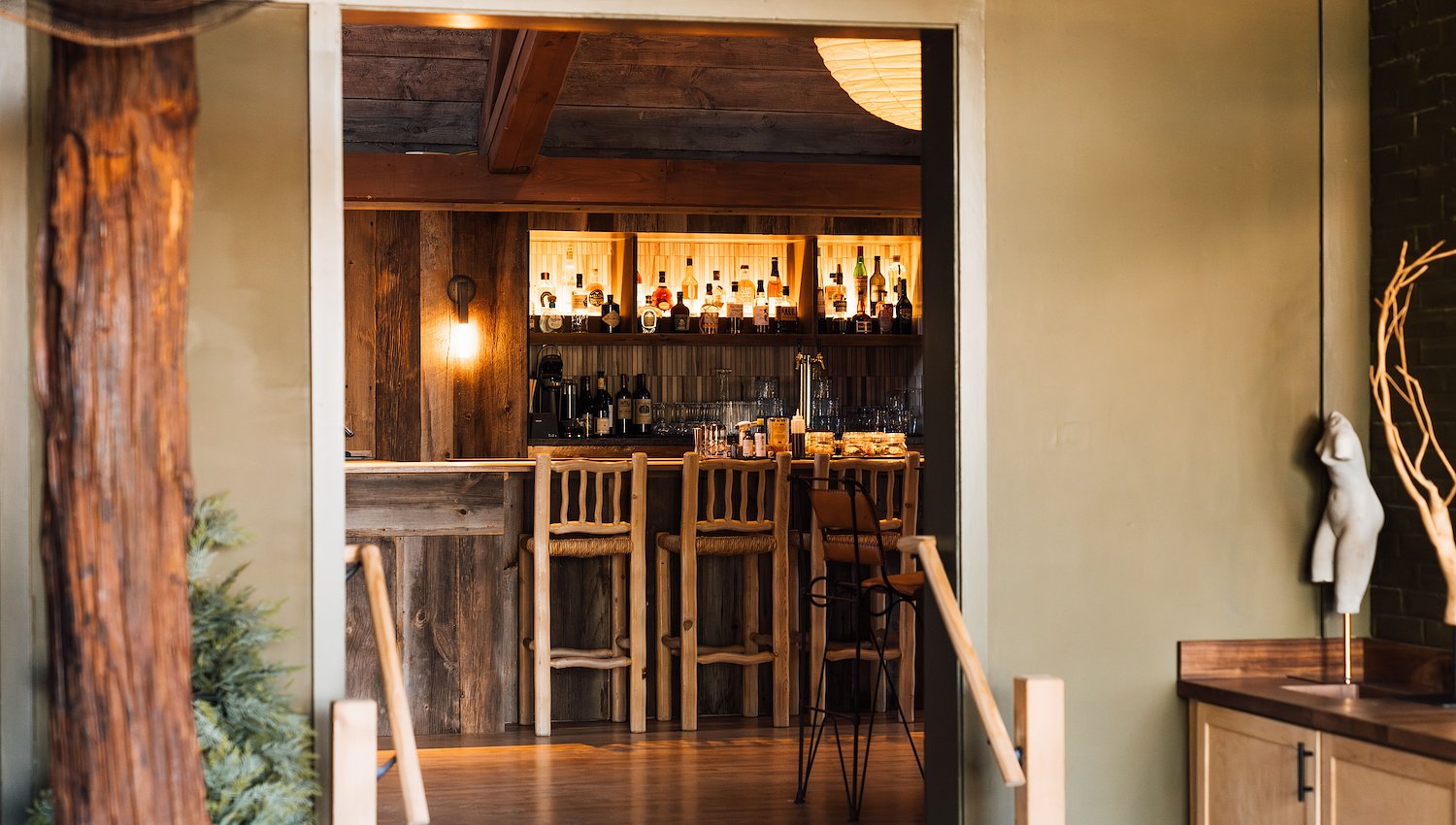 View into a cozy wooden bar area with illuminated shelves at AWOL Stowe, VT