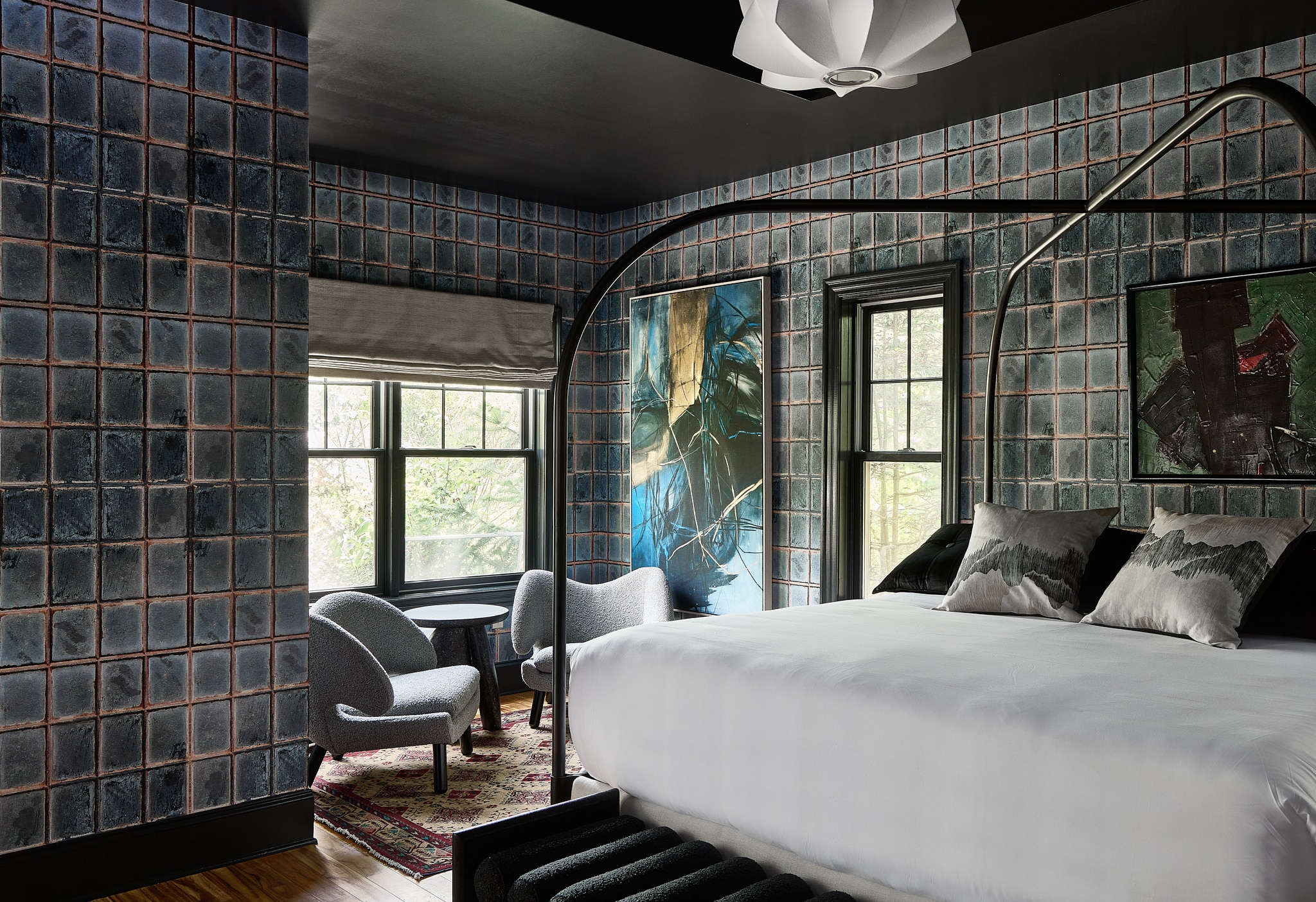A hotel room with a bed, chairs, and artwork on the walls.