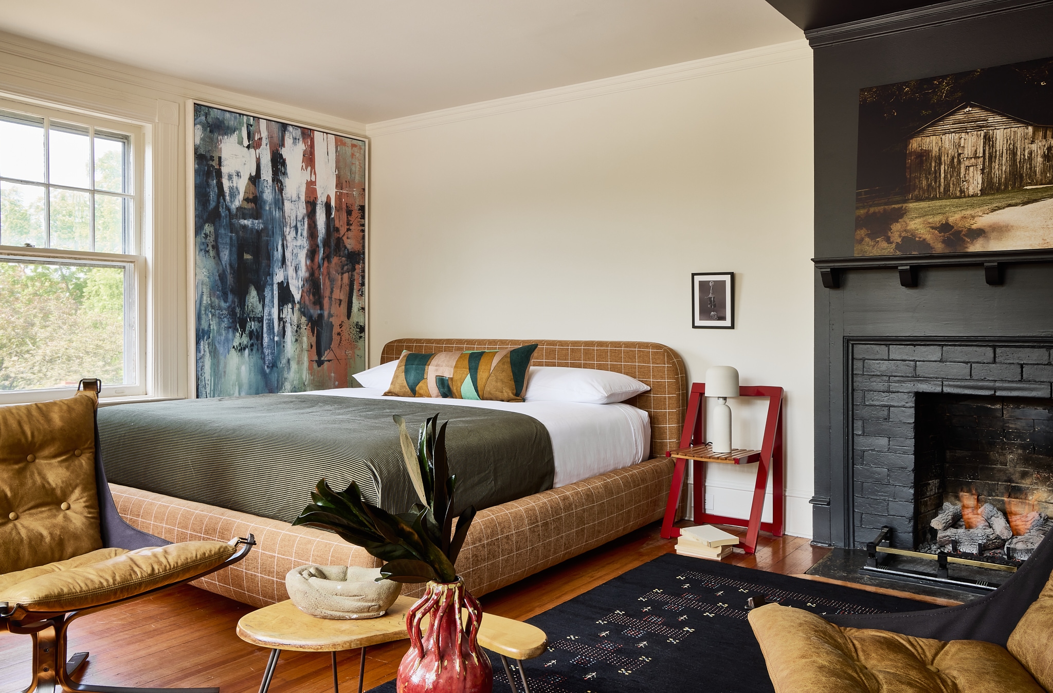 A wide view of a hotel room with a bed, fireplace, and window