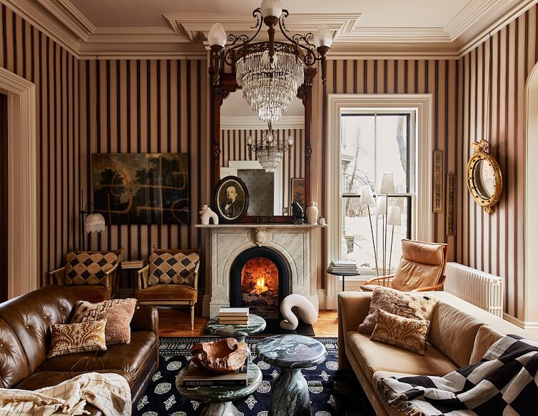 Blind Tiger Carleton lounge with a lit fireplace, leather seating, striped walls and an ornate crystal chandelier.