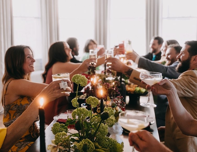 Guests raise cocktails around a candlelit dining table during a gathering at Blind Tiger.