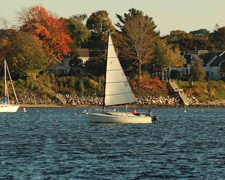  A sailboat takes during golden hour in Casco Bay in Portland, ME and surrounded by colorful fall foliage. 