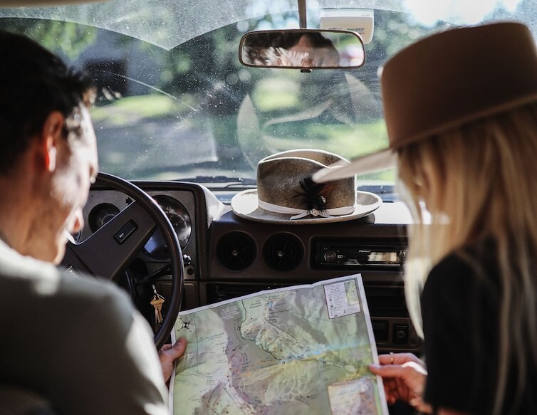 Two travelers looking at a map inside a car during a road trip.