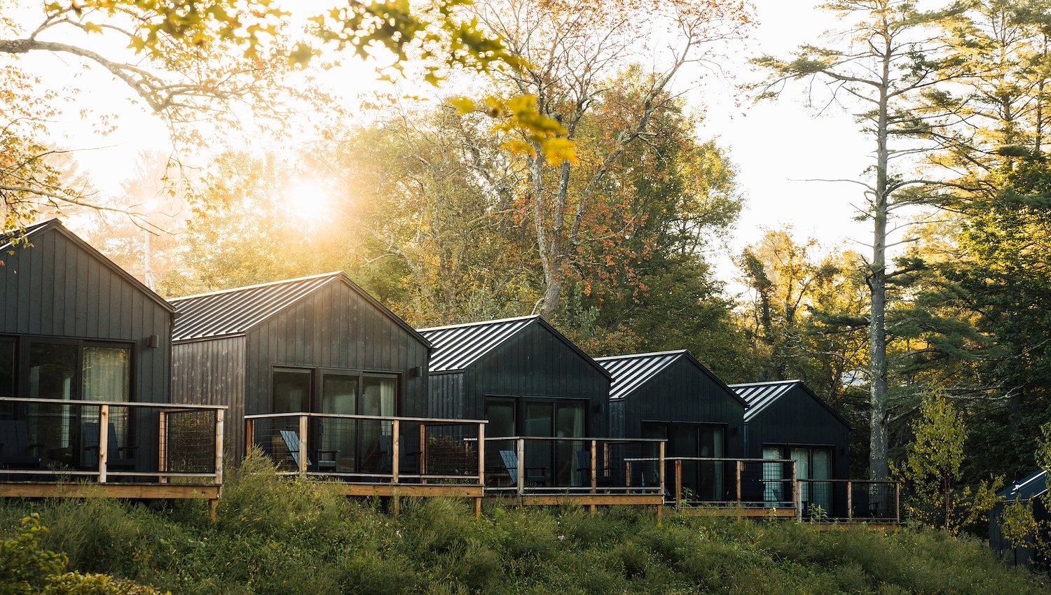 Modern guest cabins with private decks surrounded by trees in autumn.