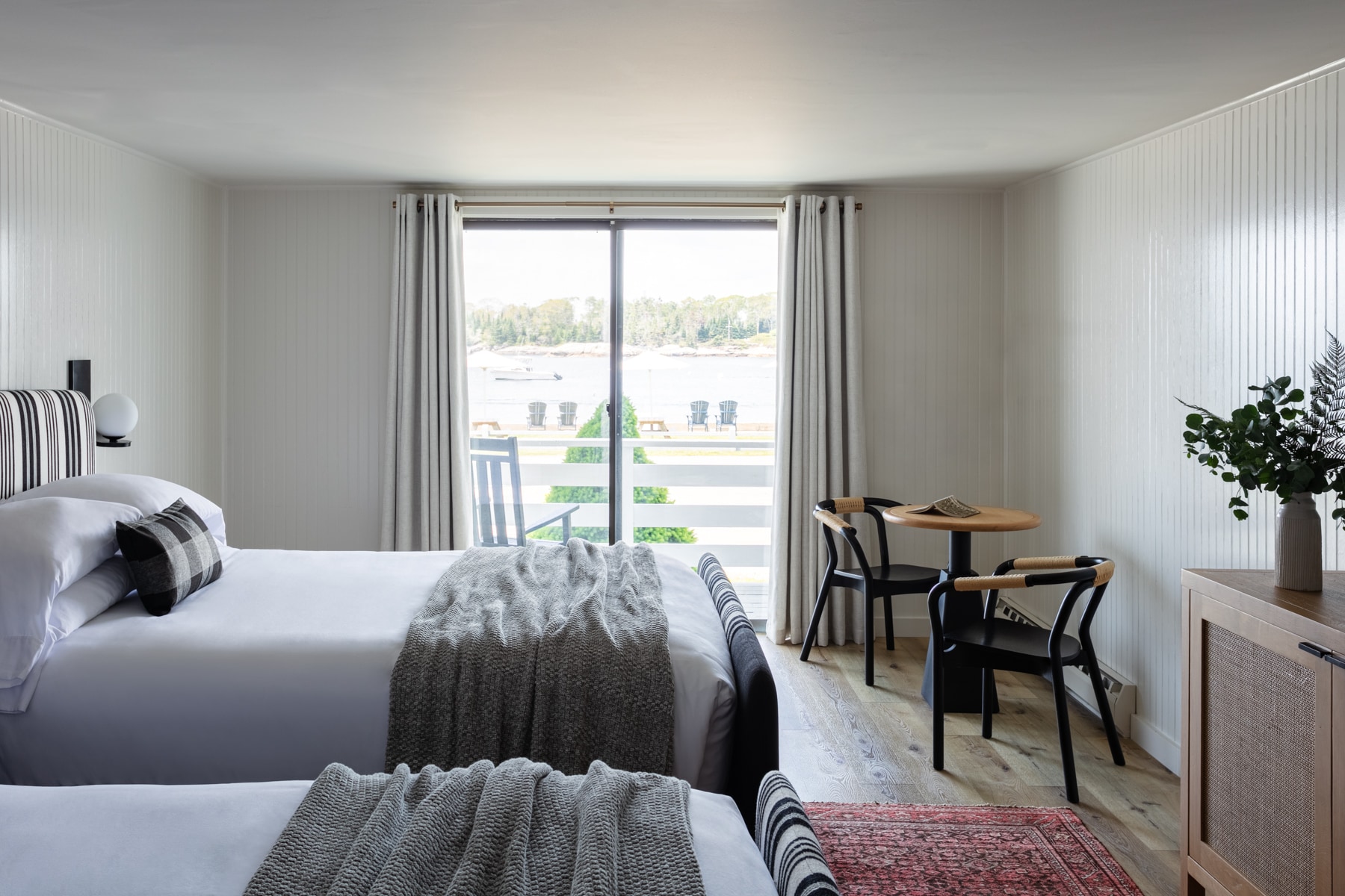 A hotel room with a bed, table, chairs, and a window with a view.