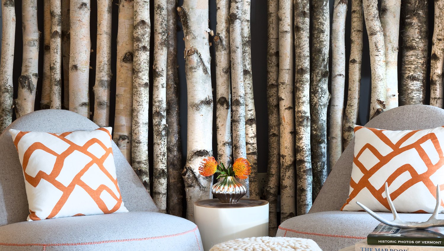 Two armchairs with a birch log wall