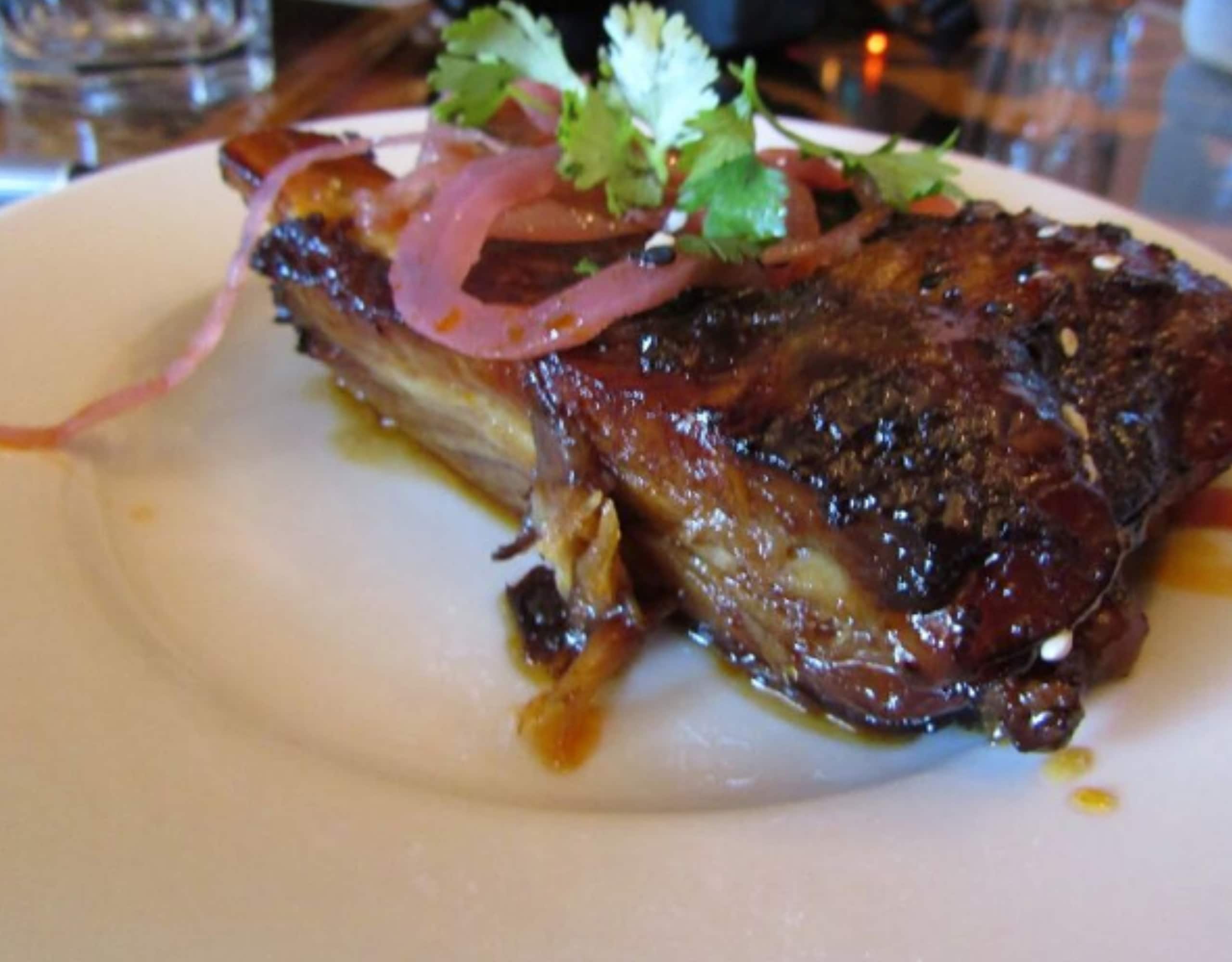 a plated dish of meat with sauce and garnish
