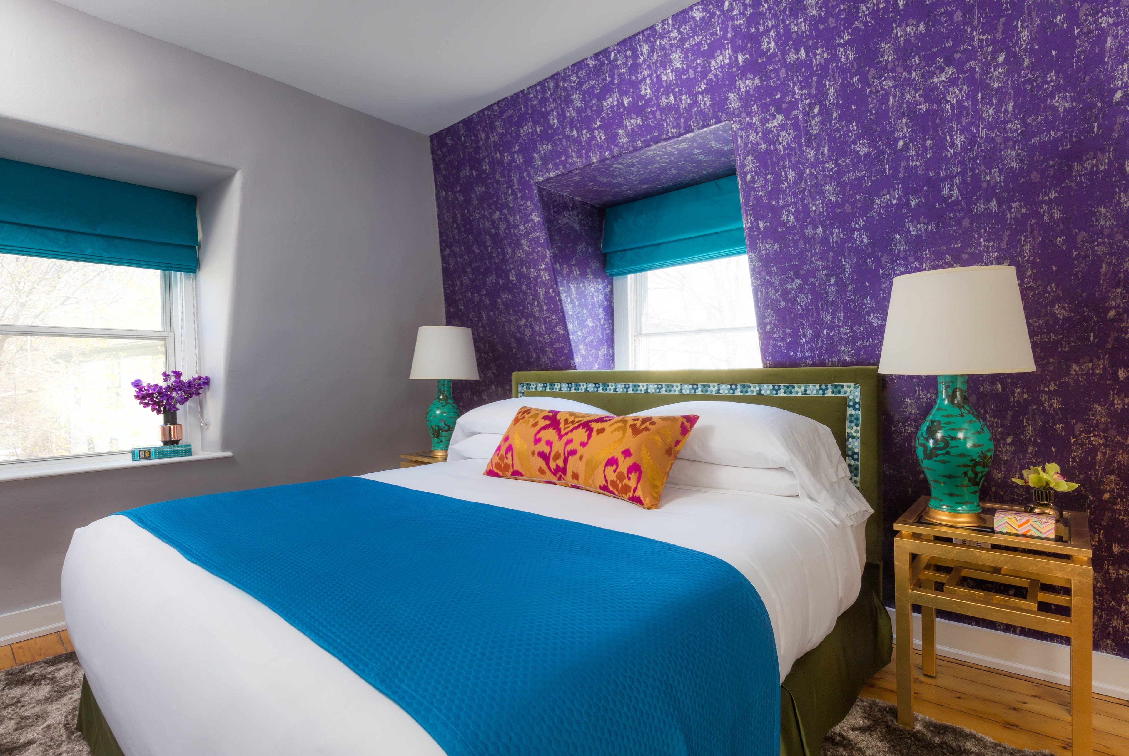 A bedroom with a bed, two nightstands, two lamps, and a window.