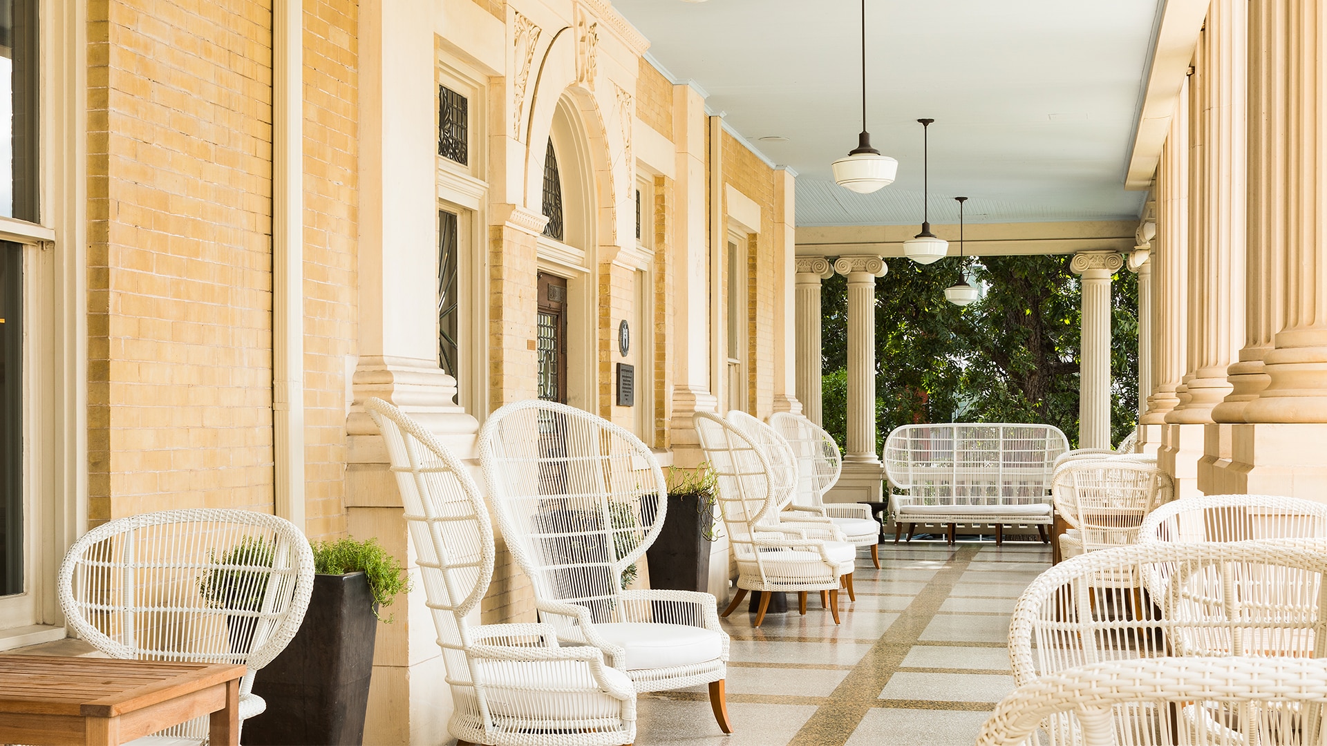 A covered porch with white wicker furniture and columns