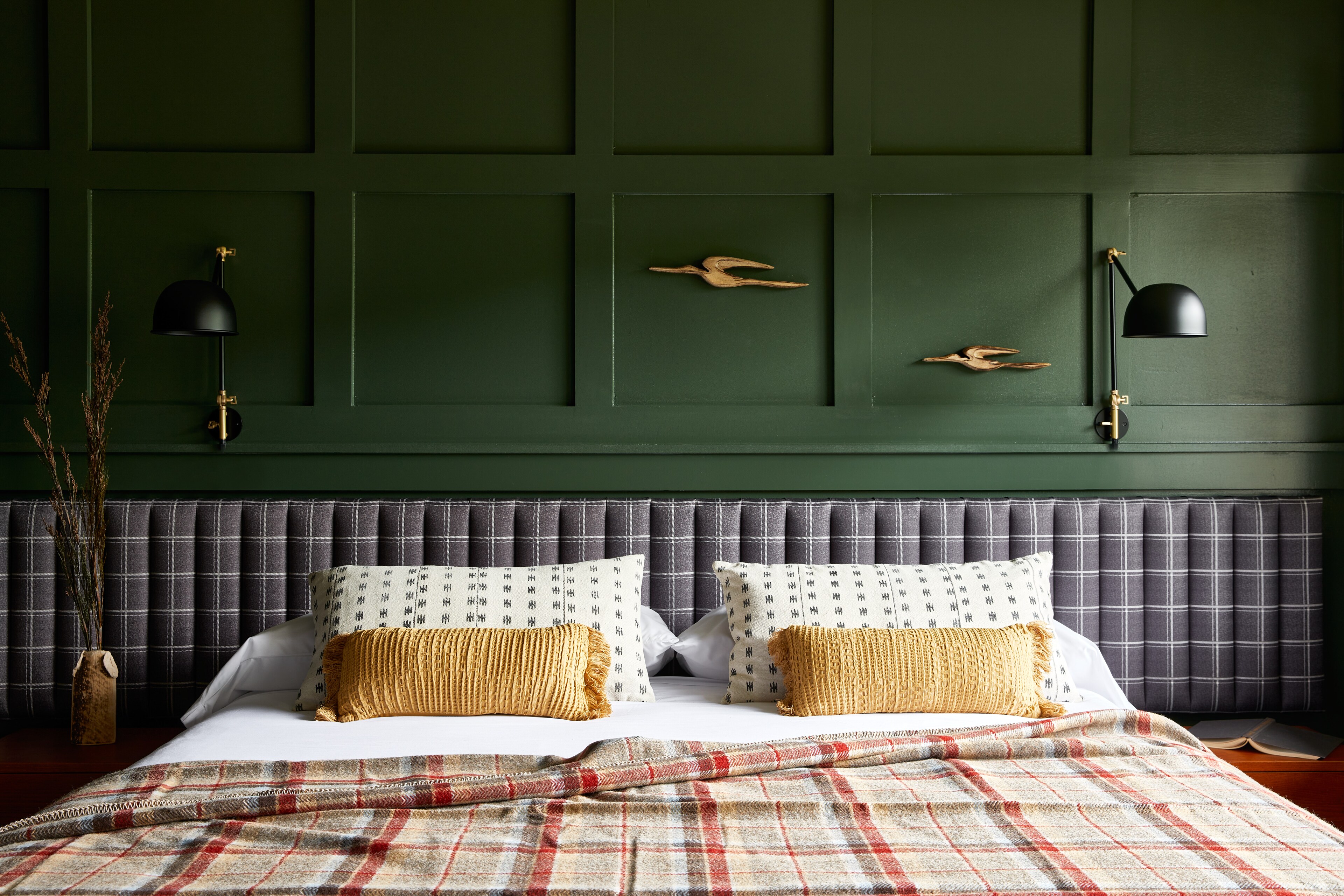 a bed with a plaid headboard and green wall