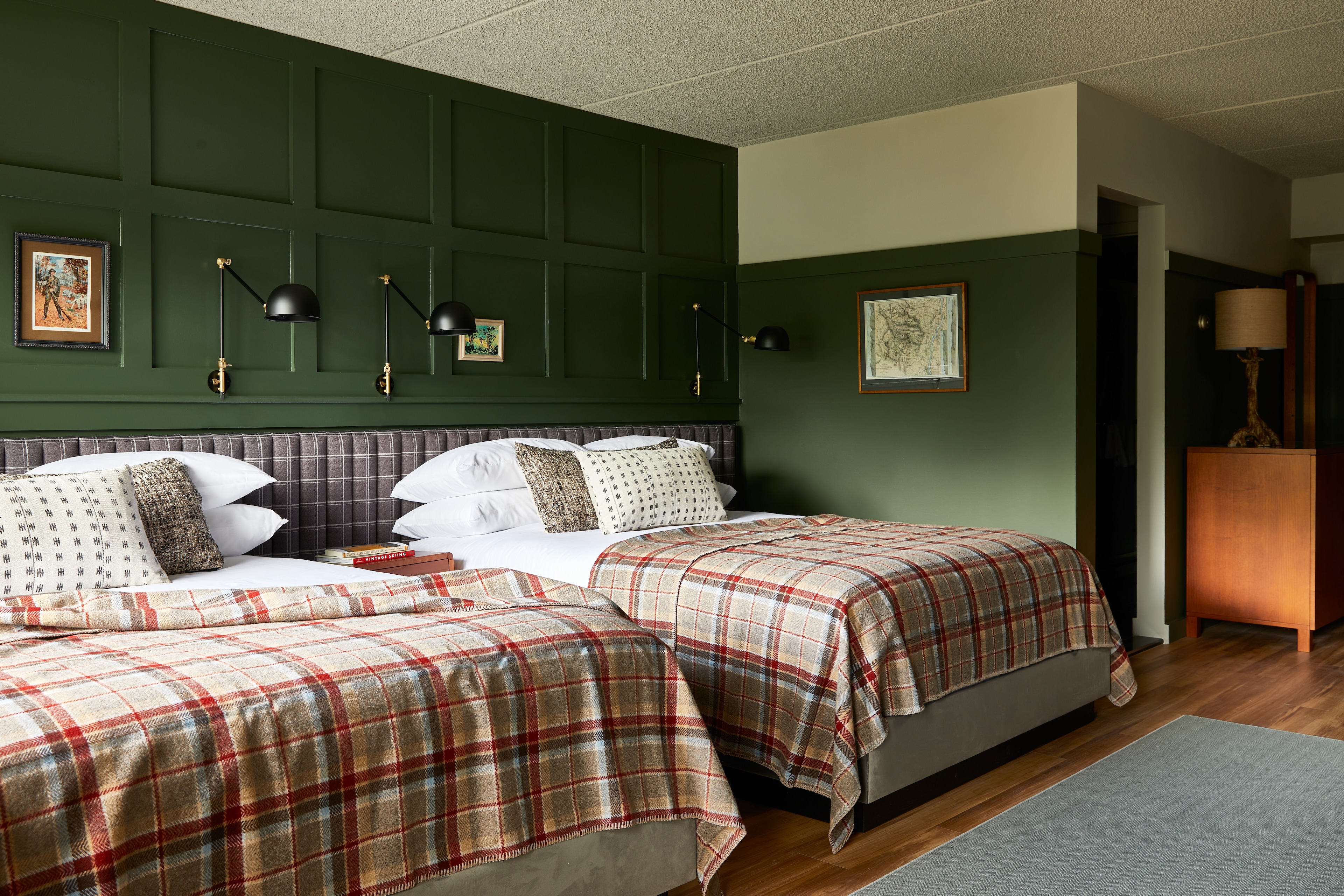 A hotel room with two beds, green walls, and a wooden floor