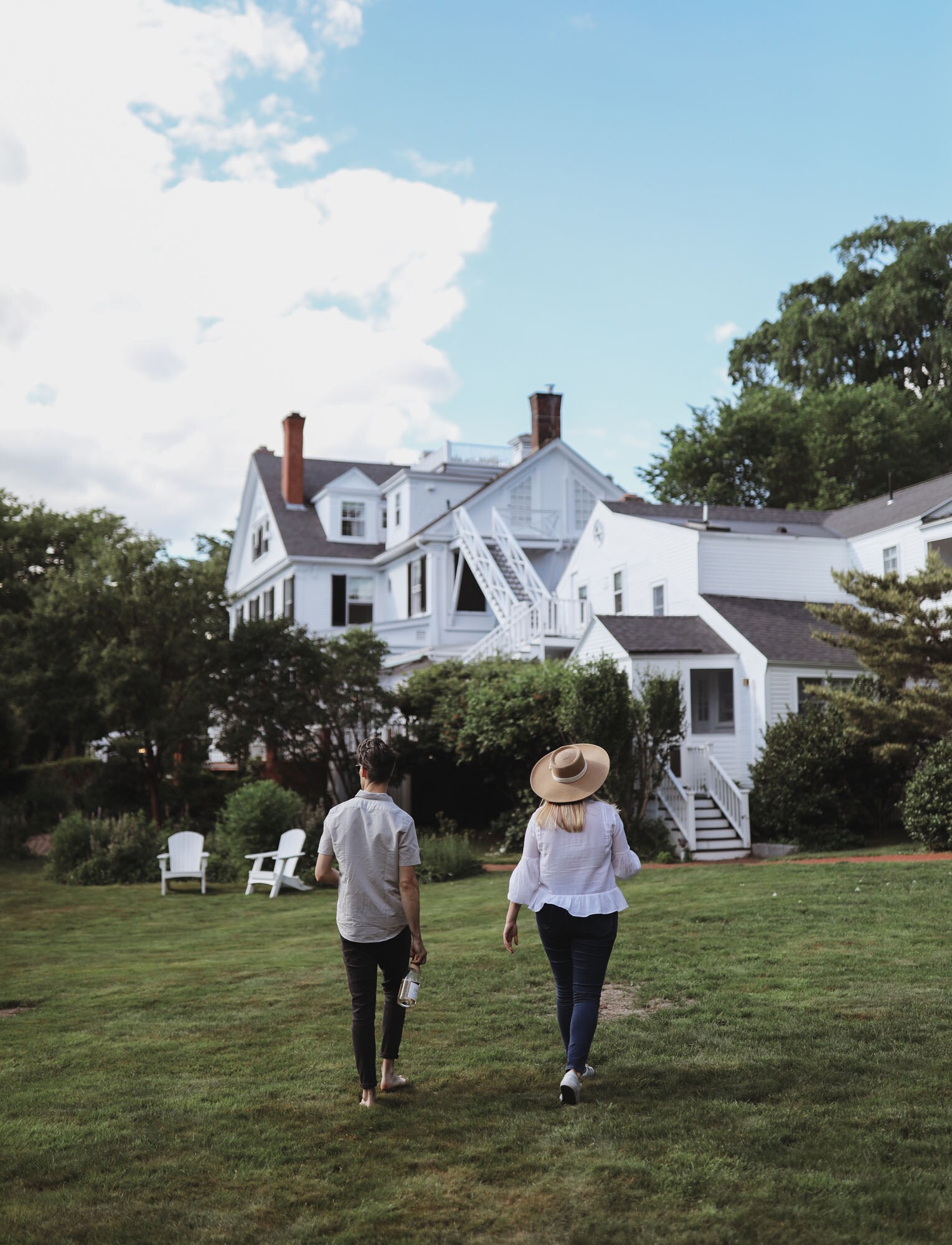 A couple walks toward a white historic home in Kennebunkport ME