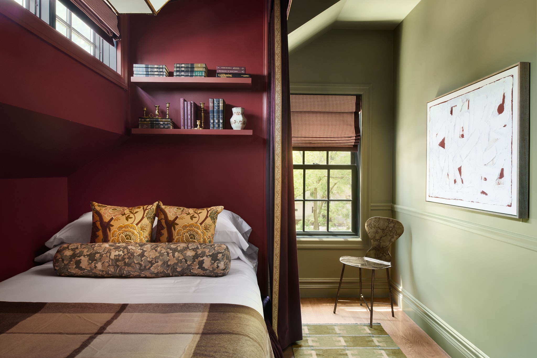 A cozy guest room with a bed, window, bookshelf, and chair.