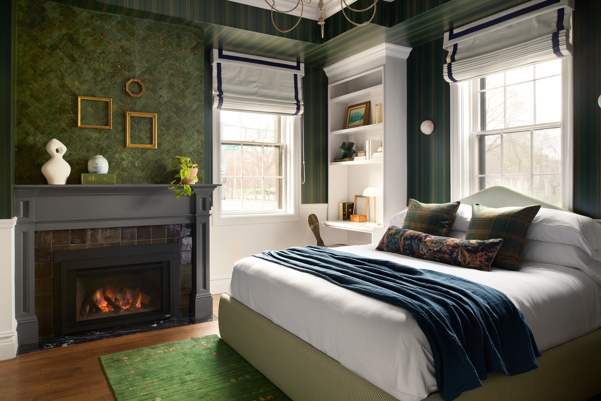 A guest room with a bed, fireplace, window, and bookshelf.