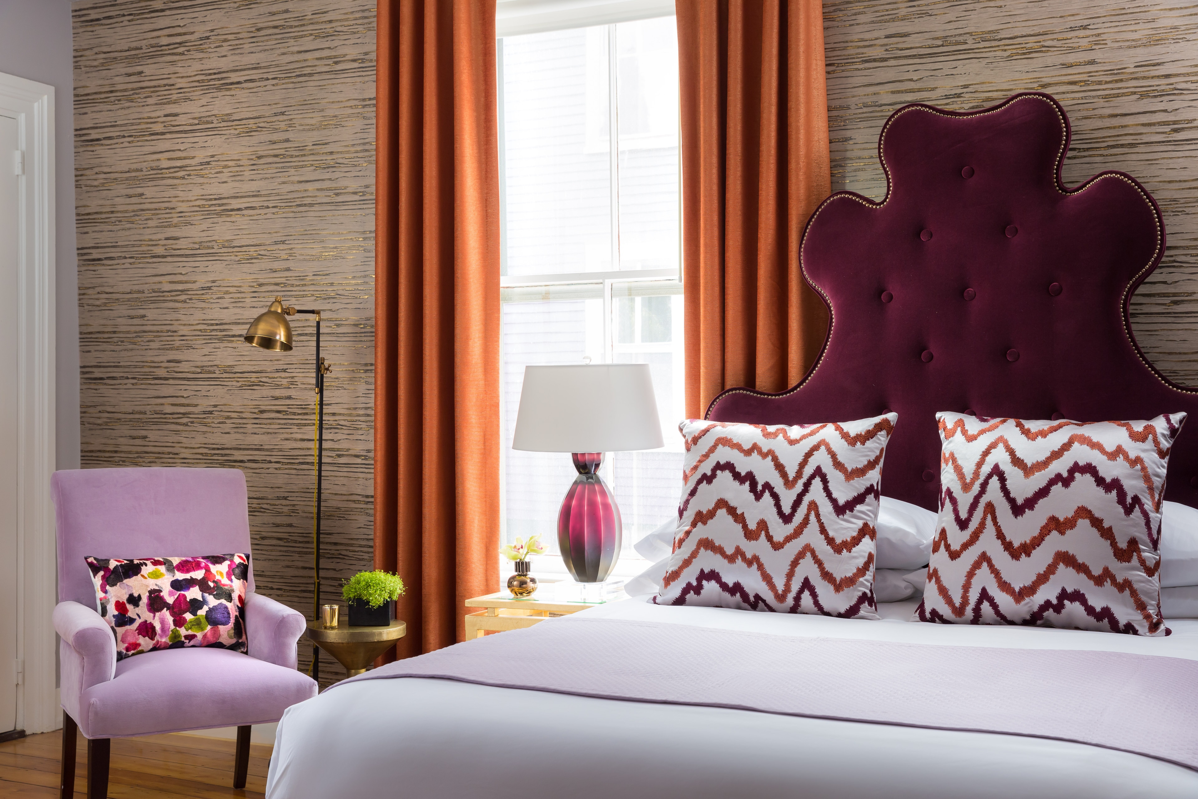 A hotel room with a large bed, chair, and window