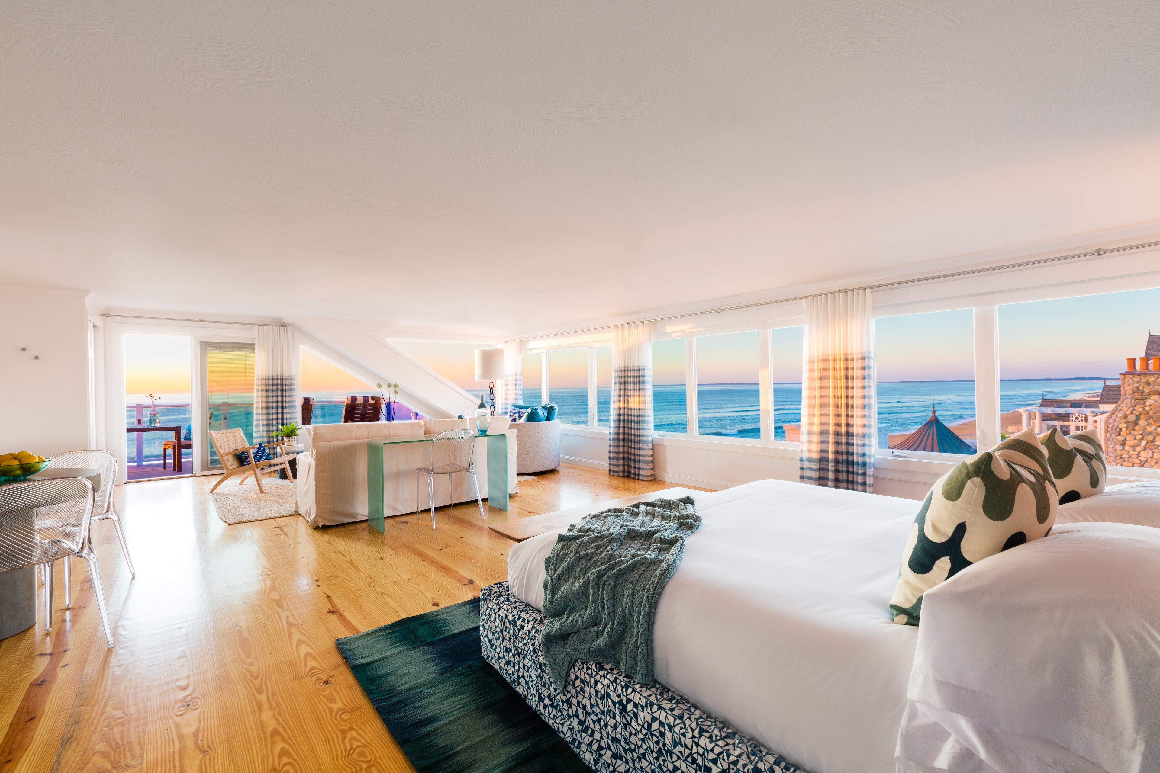 A wide room with a large bed, sofa, and balcony with a sea view.