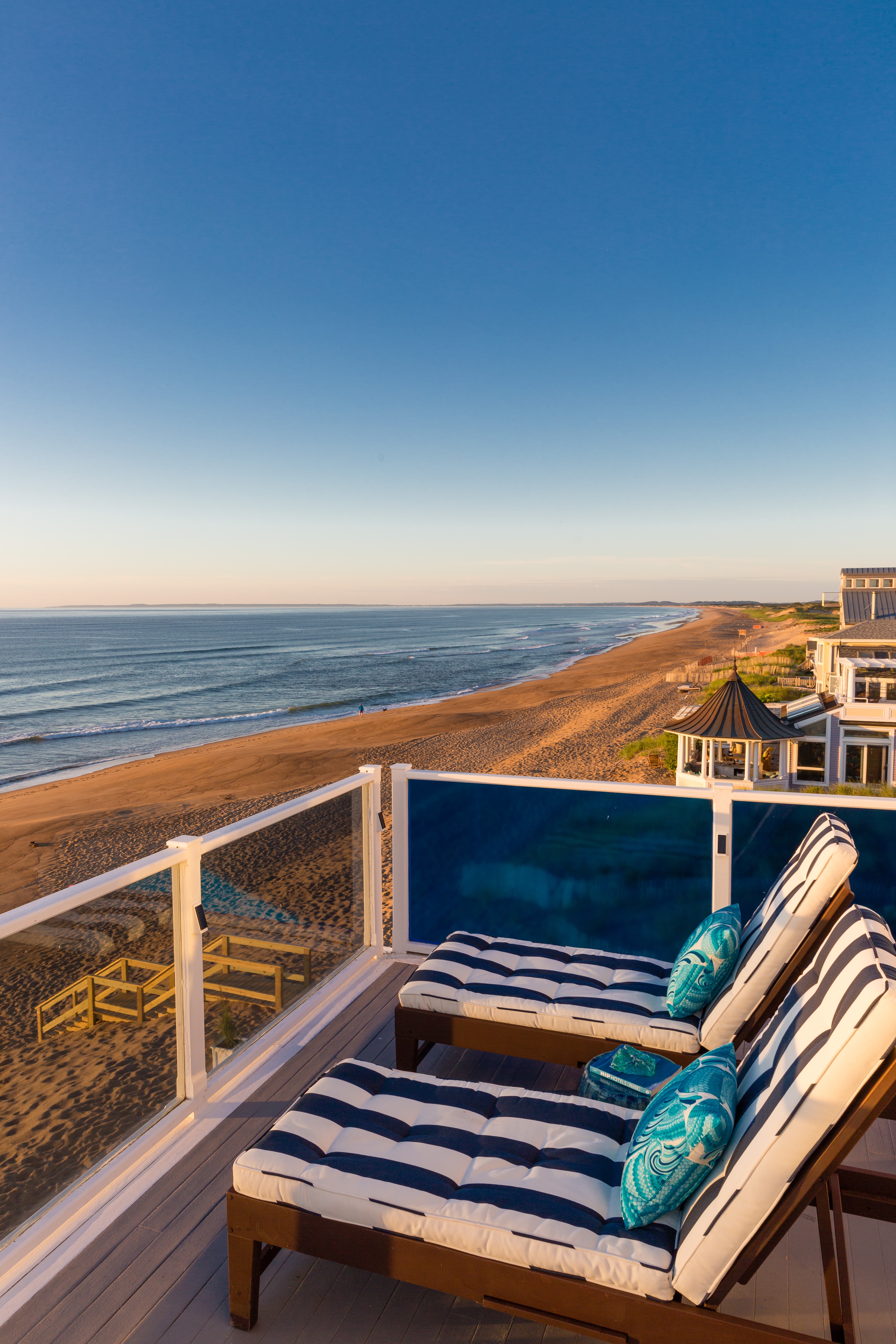 A beachside deck with lounge chairs overlooking the ocean.