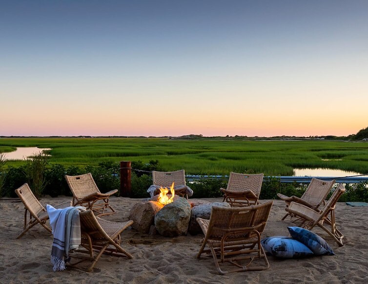 Outdoor fire pit seating overlooking a marsh at sunset