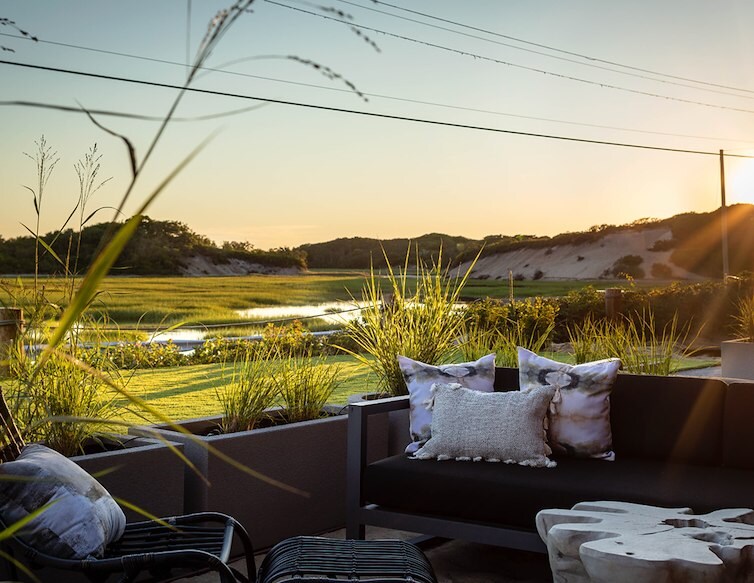 cozy patio featuring a comfortable couch and a stylish table, surrounded by greenery and sunlight.