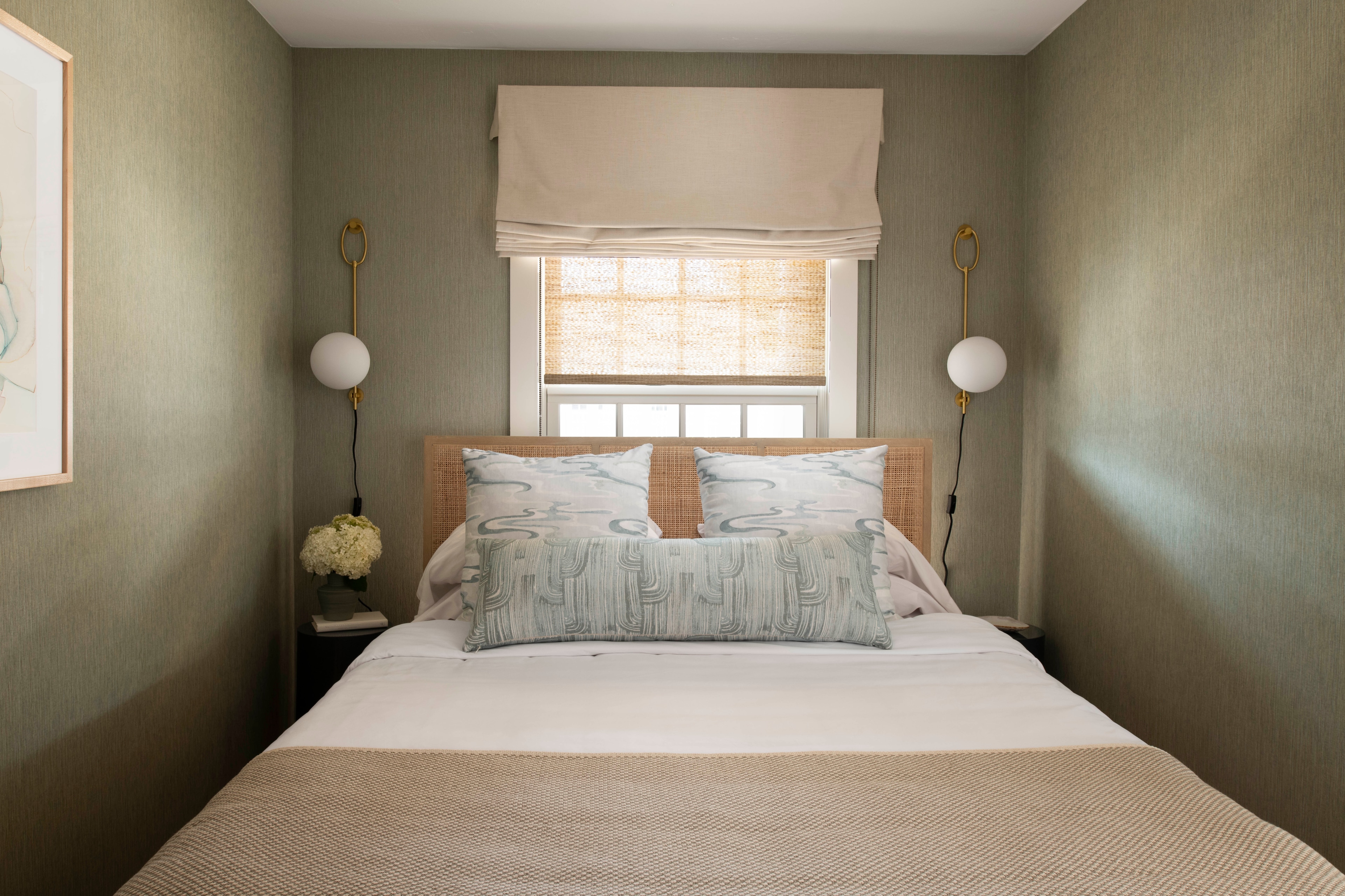 A neatly made bed with pillows and a window in the background