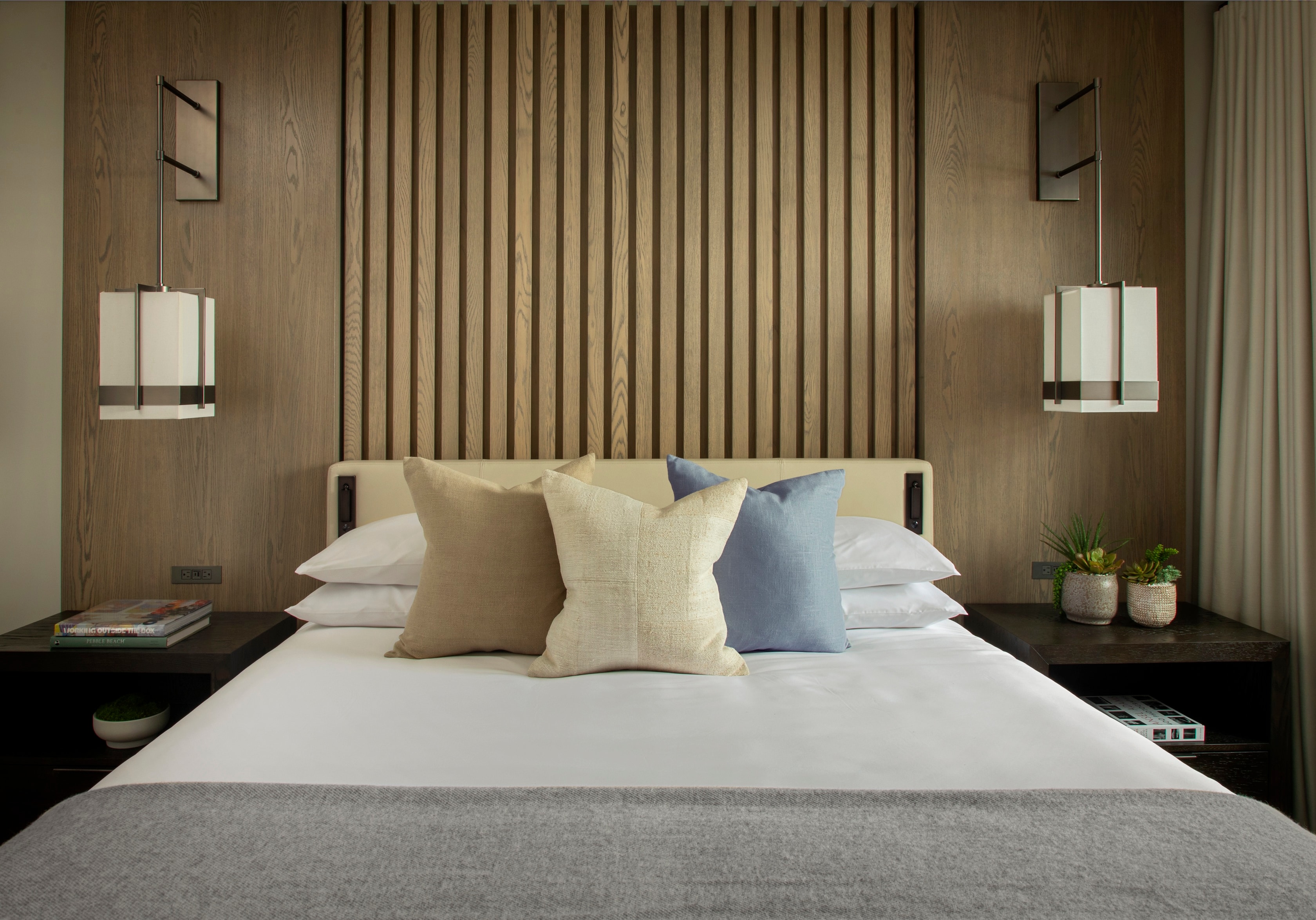 A neatly made bed with pillows and a wooden headboard in a room with modern decor.