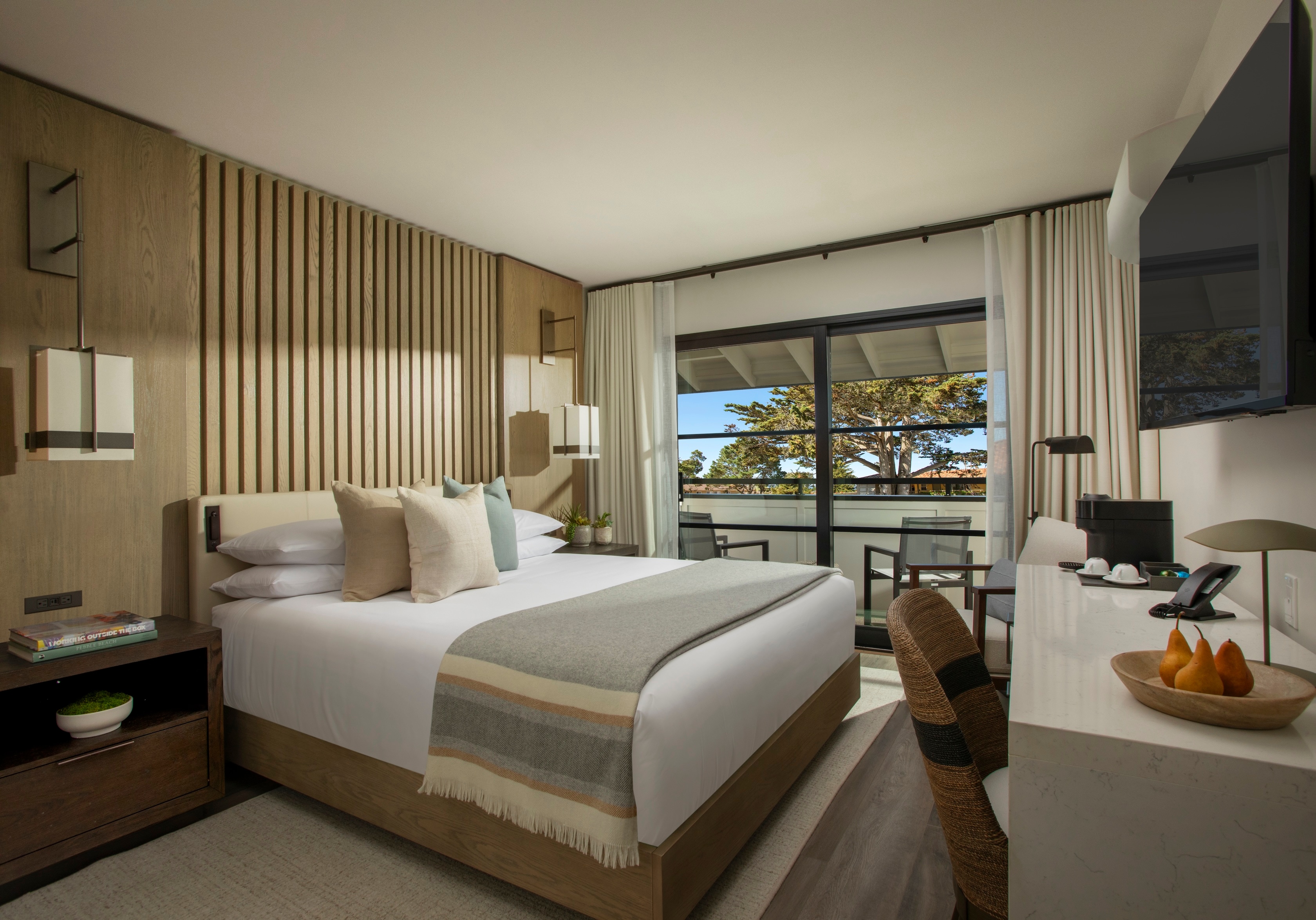 A hotel room with a bed, desk, and window
