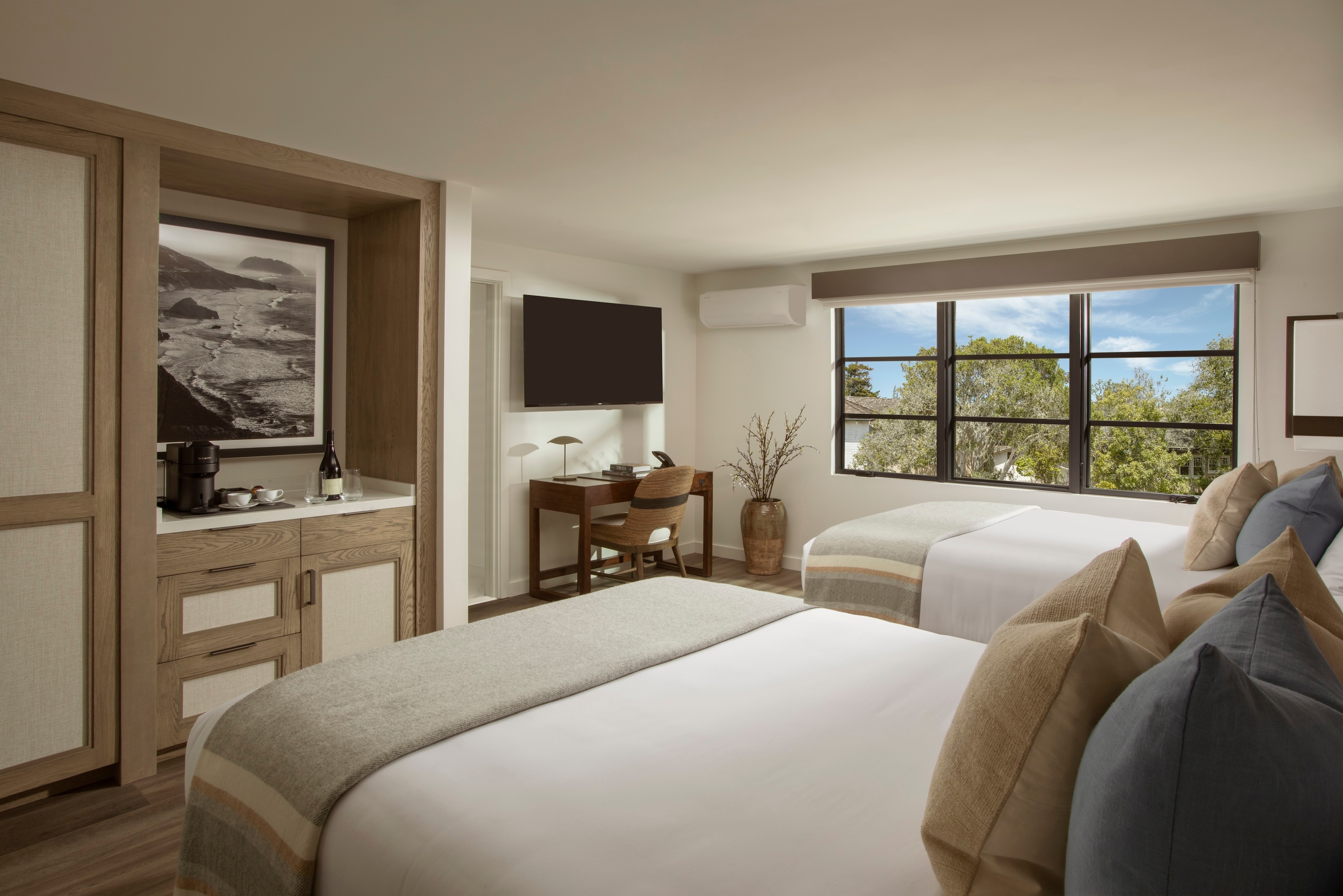 A hotel room with a double bed, window, desk, TV, and coffee maker.