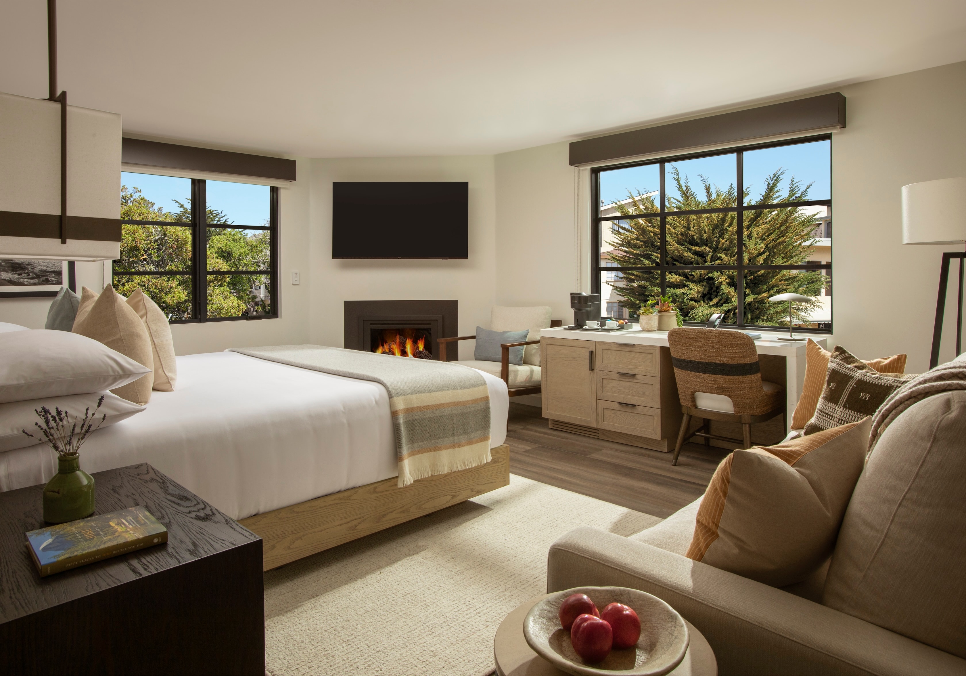 A hotel room with a bed, fireplace, desk, and TV