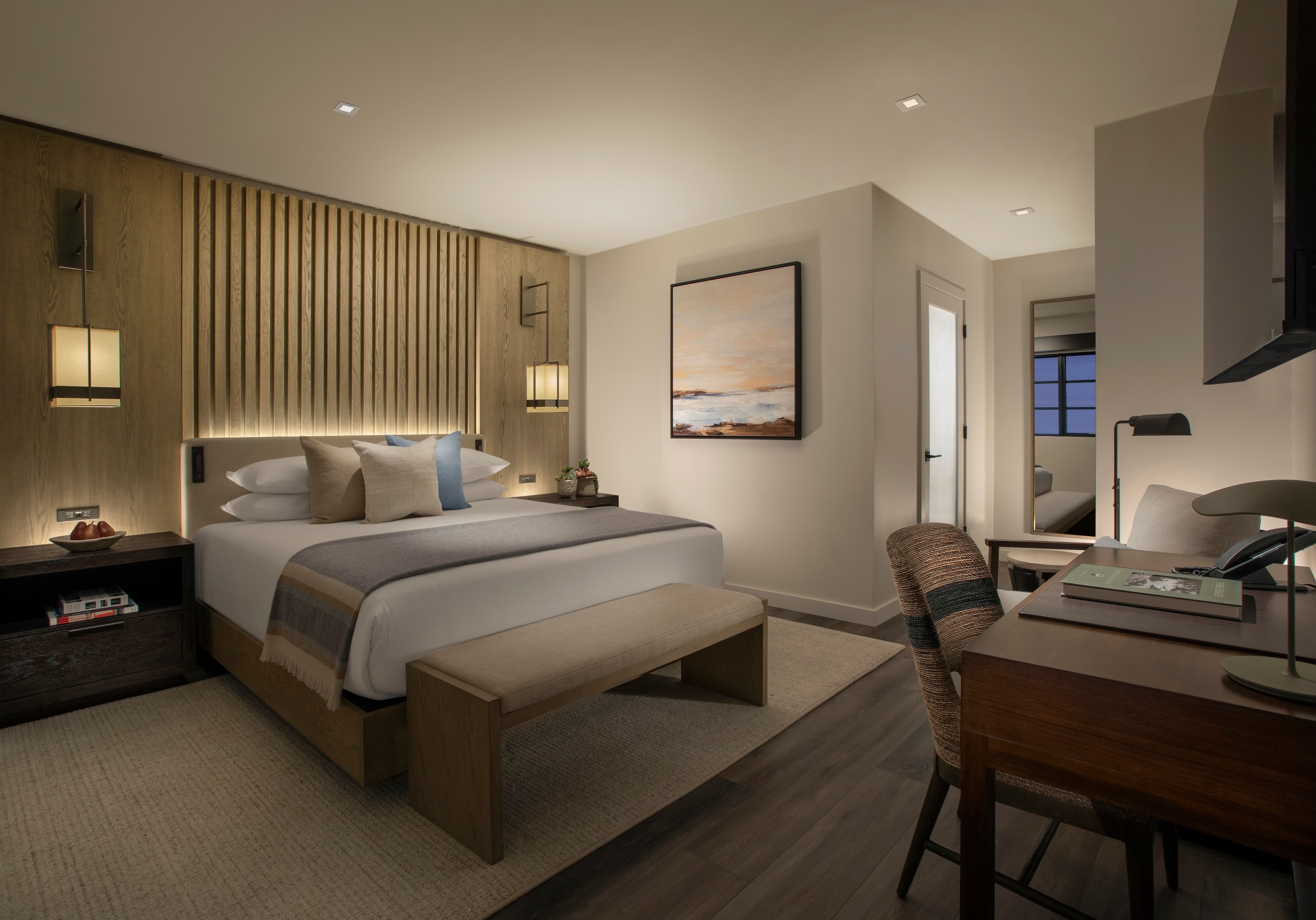 A hotel room with a bed, desk, and chair.