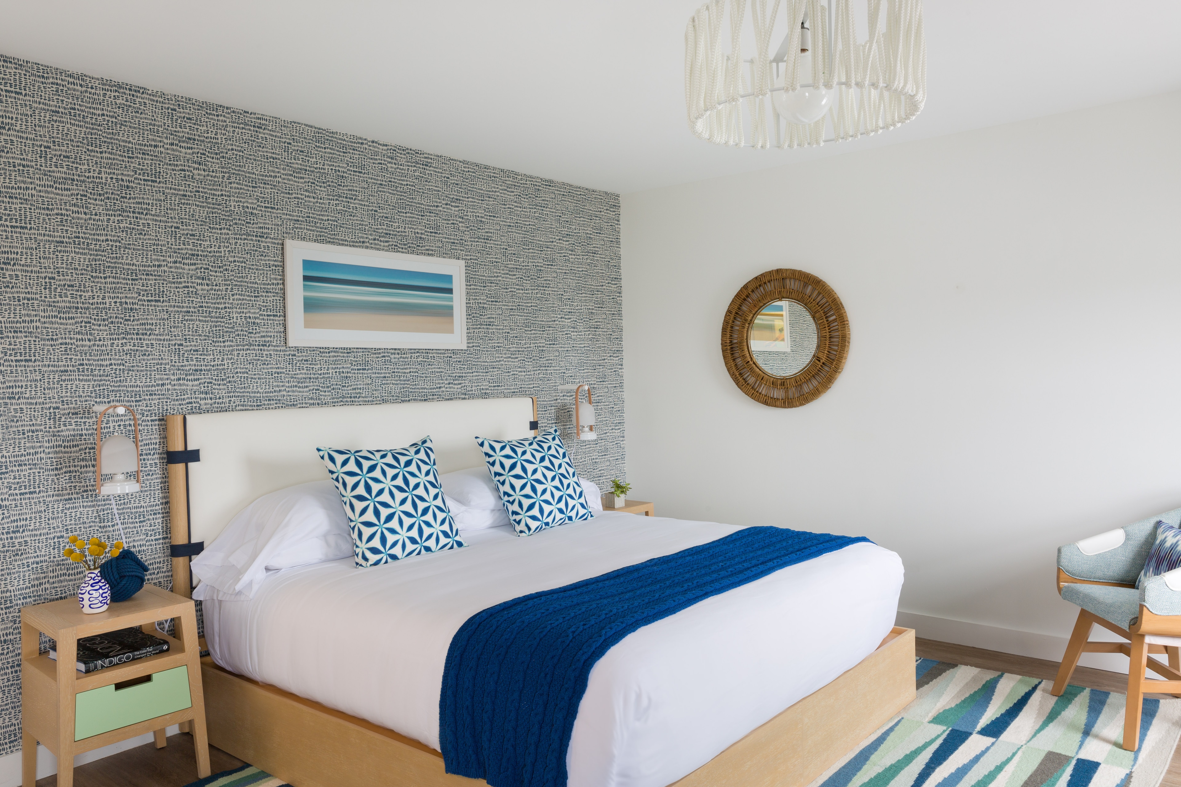 A neatly made bed with white linens and blue accents in a cozy room.