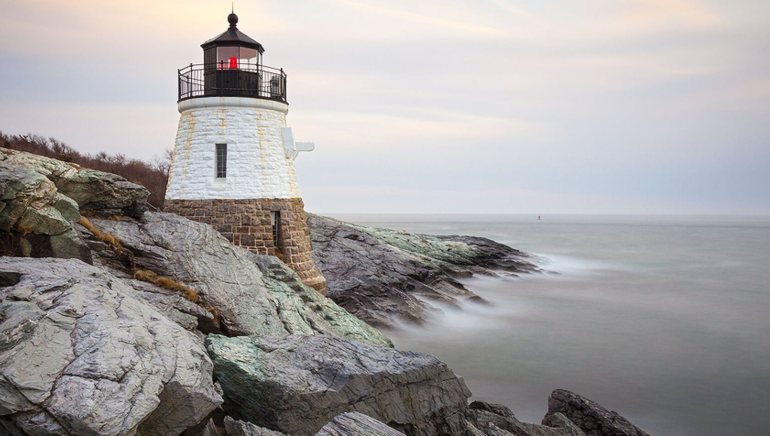 Shoreline with lighthouse at dawn on the rocky coast of Newport, Rhode Island