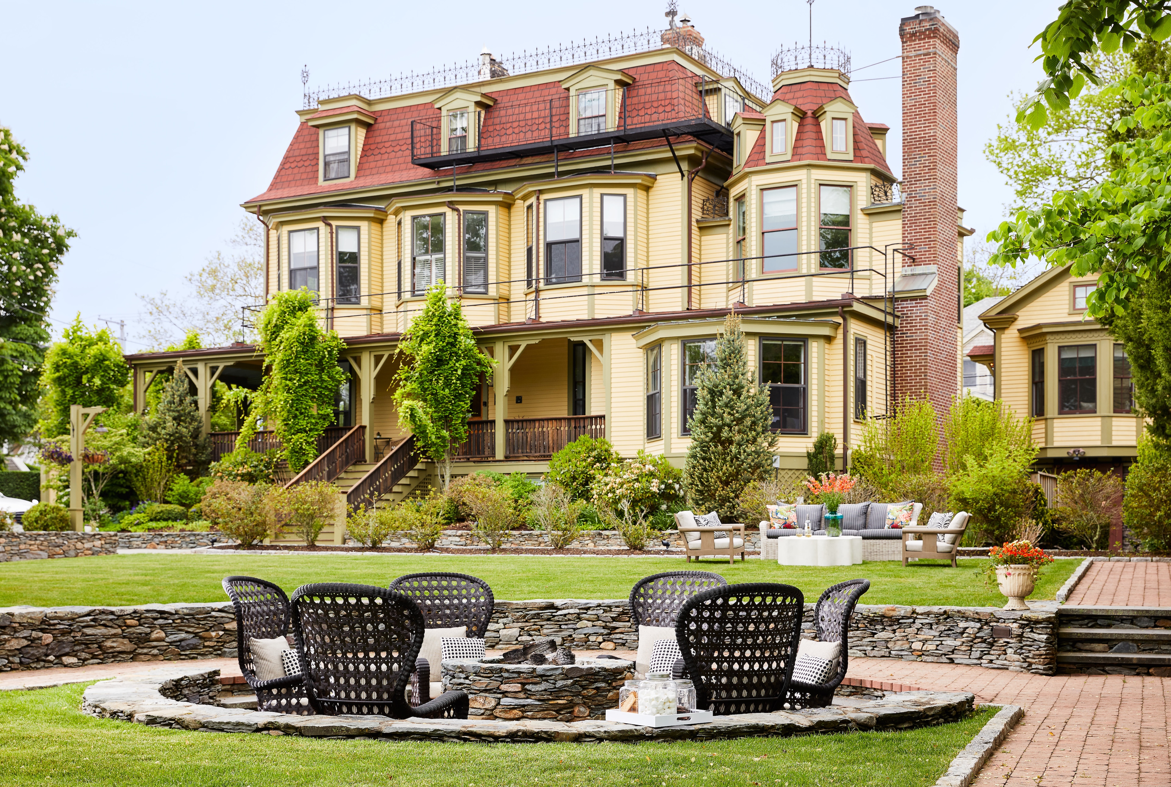 A large house with a red roof and a fire pit in the yard.
