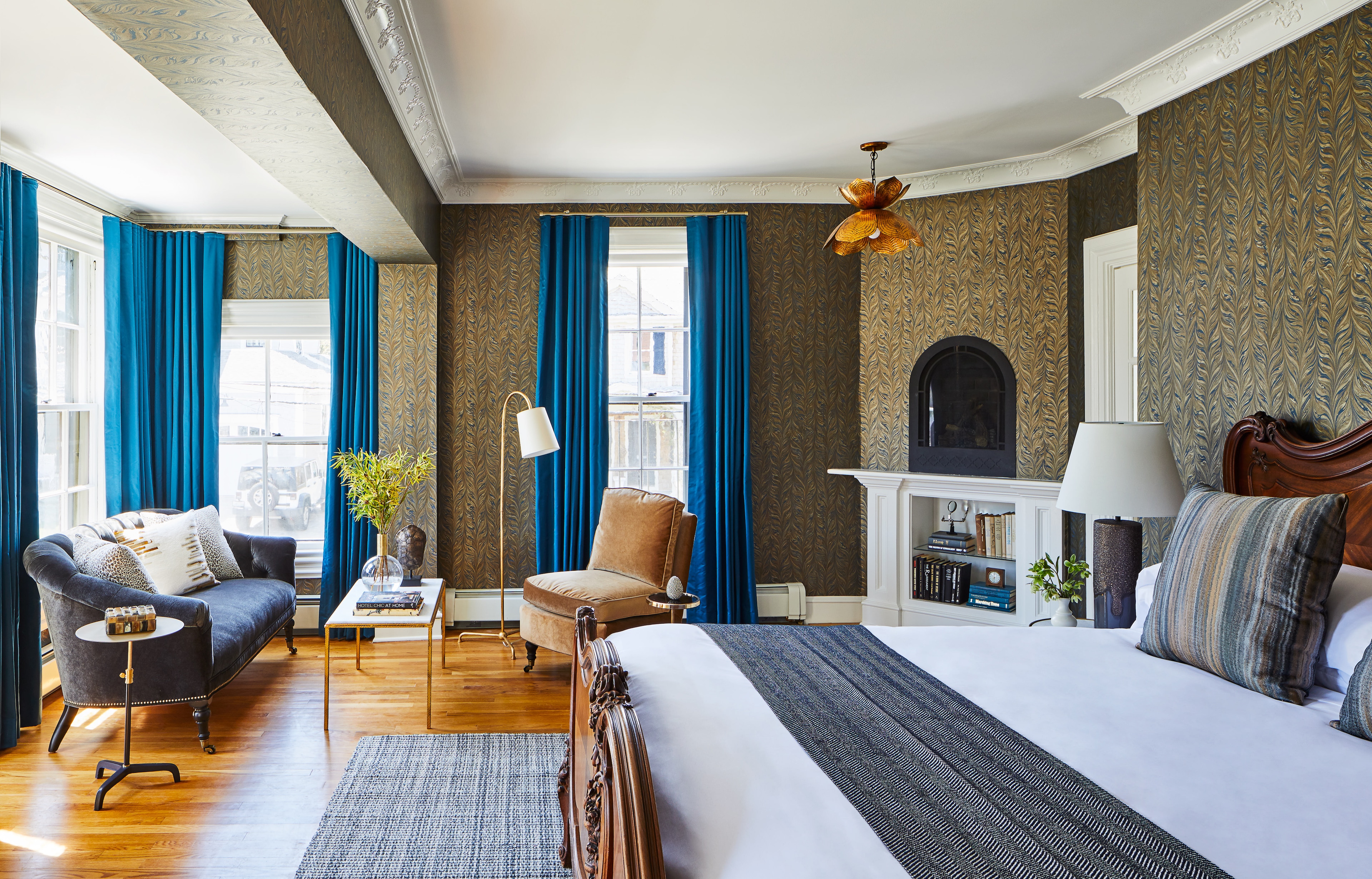 A luxurious hotel room with a sitting area, fireplace, and large bed.