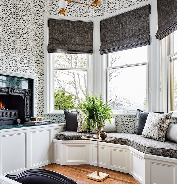 A cozy corner nook with a built-in bench, fireplace, and windows.