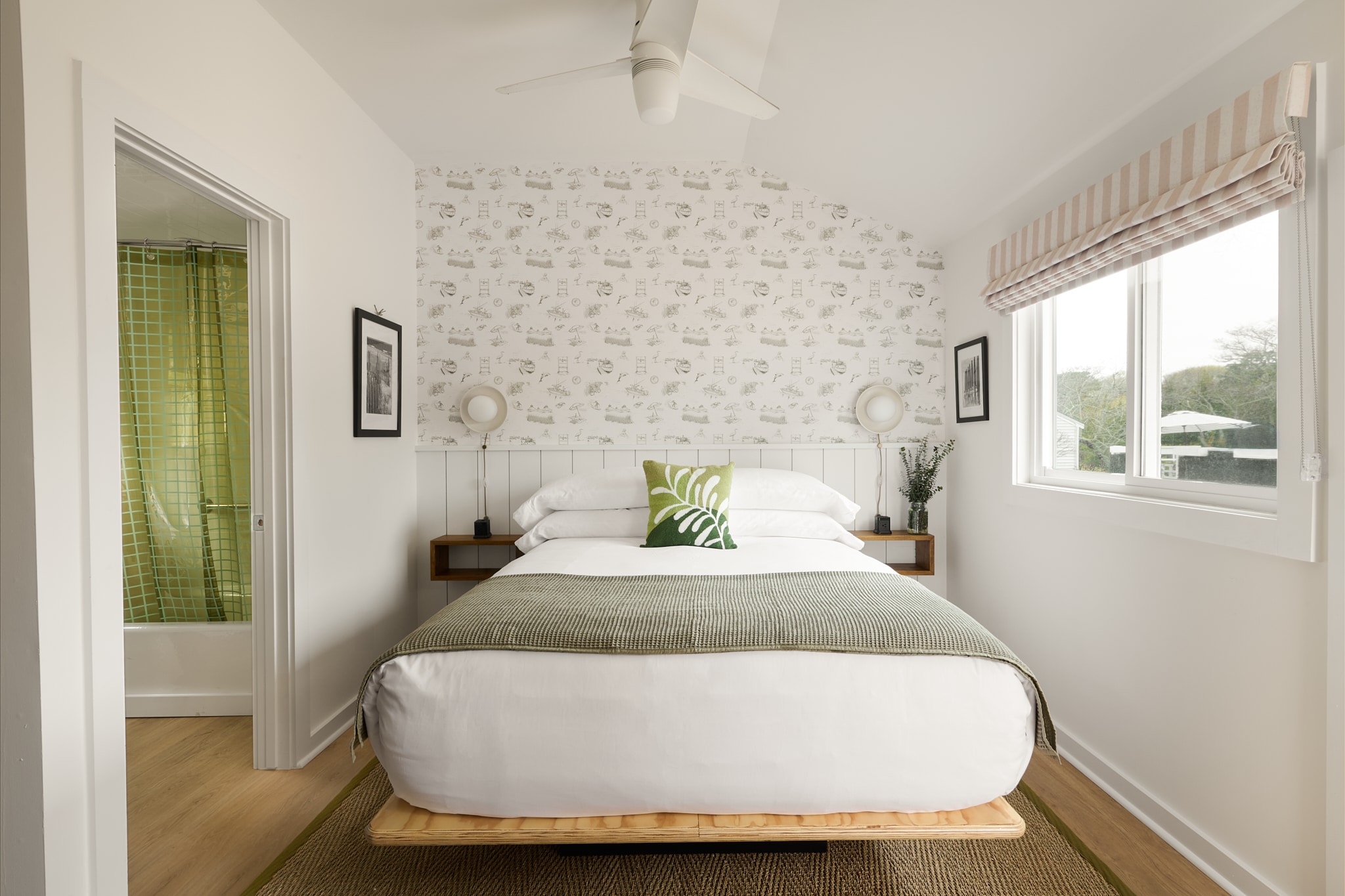 A clean and cozy bedroom with a large bed, a window, and a doorway to the bathroom.