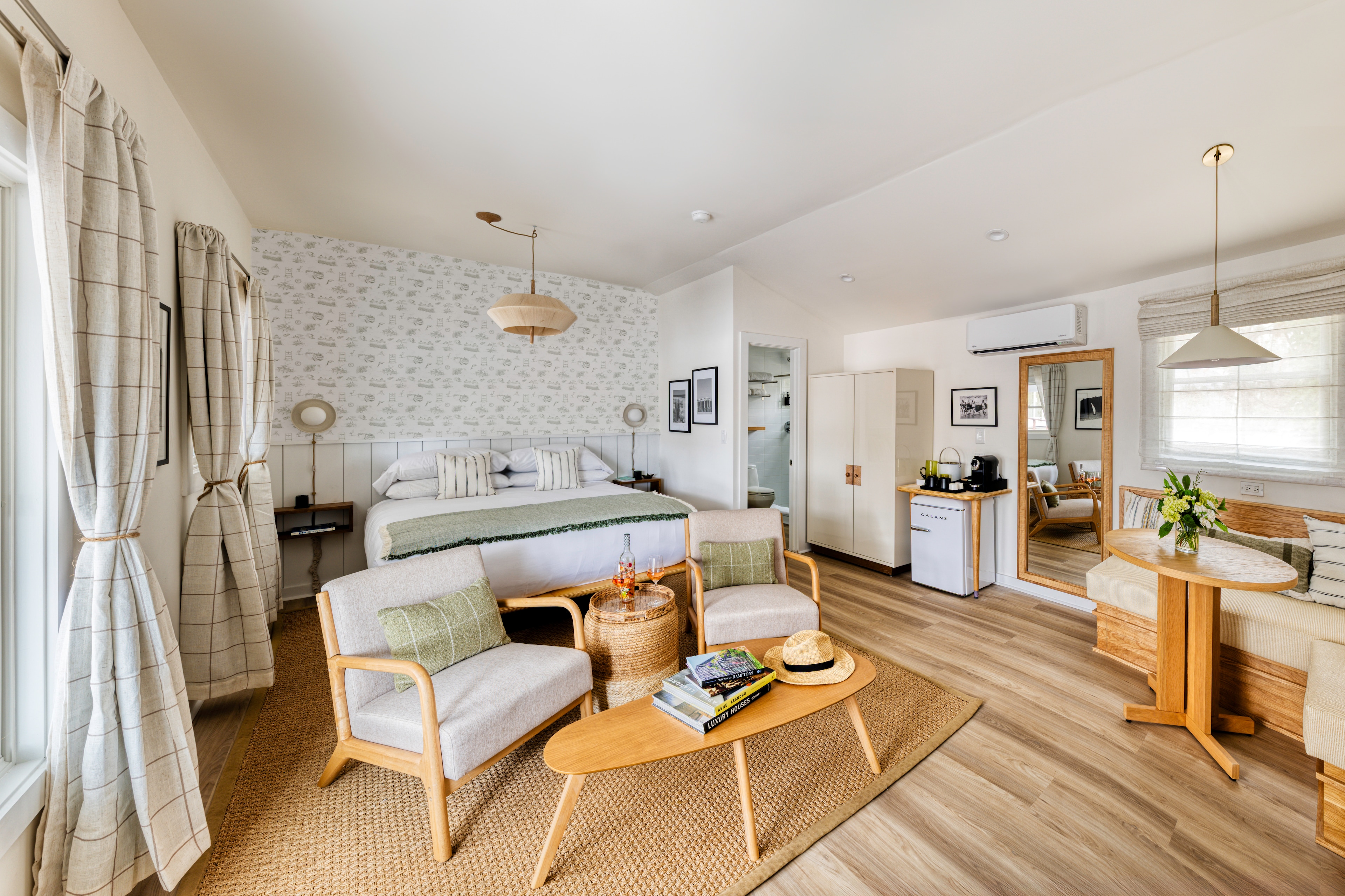 A wide view of a stylish hotel room with a sitting area and a bed