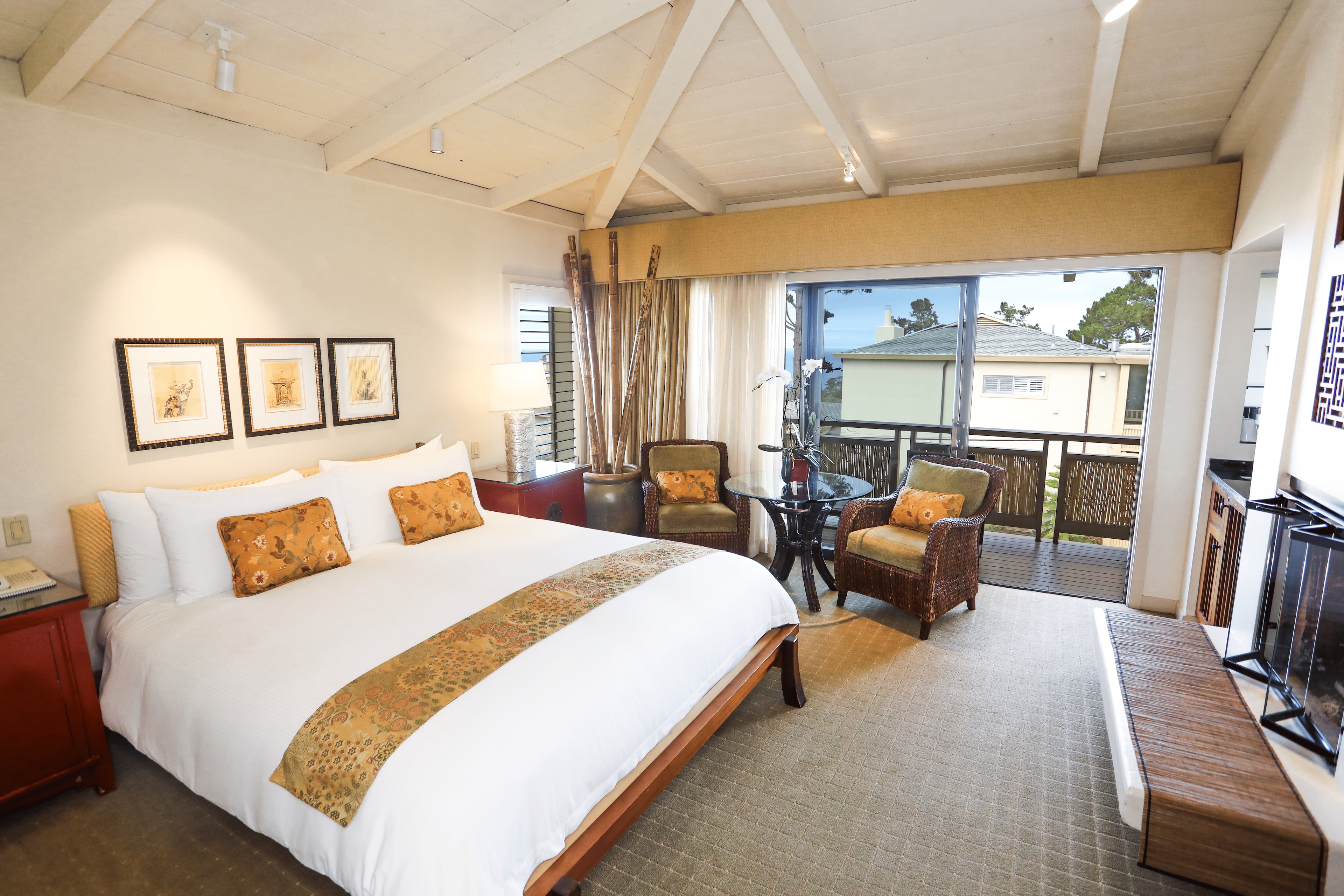 A hotel room with a bed, two chairs, a table, and a TV