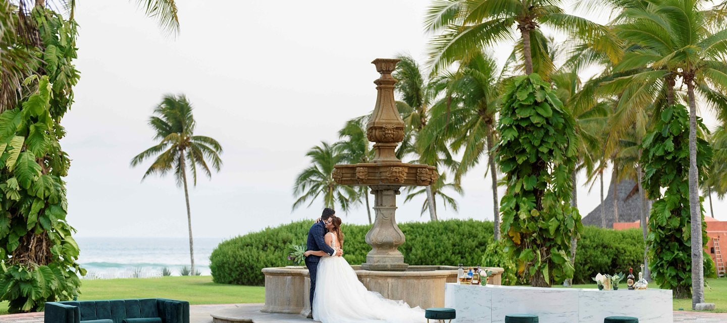 Una pareja se abraza en un entorno de jardín romántico en el Resort Las Alamandas, Costalegre, Jalisco
