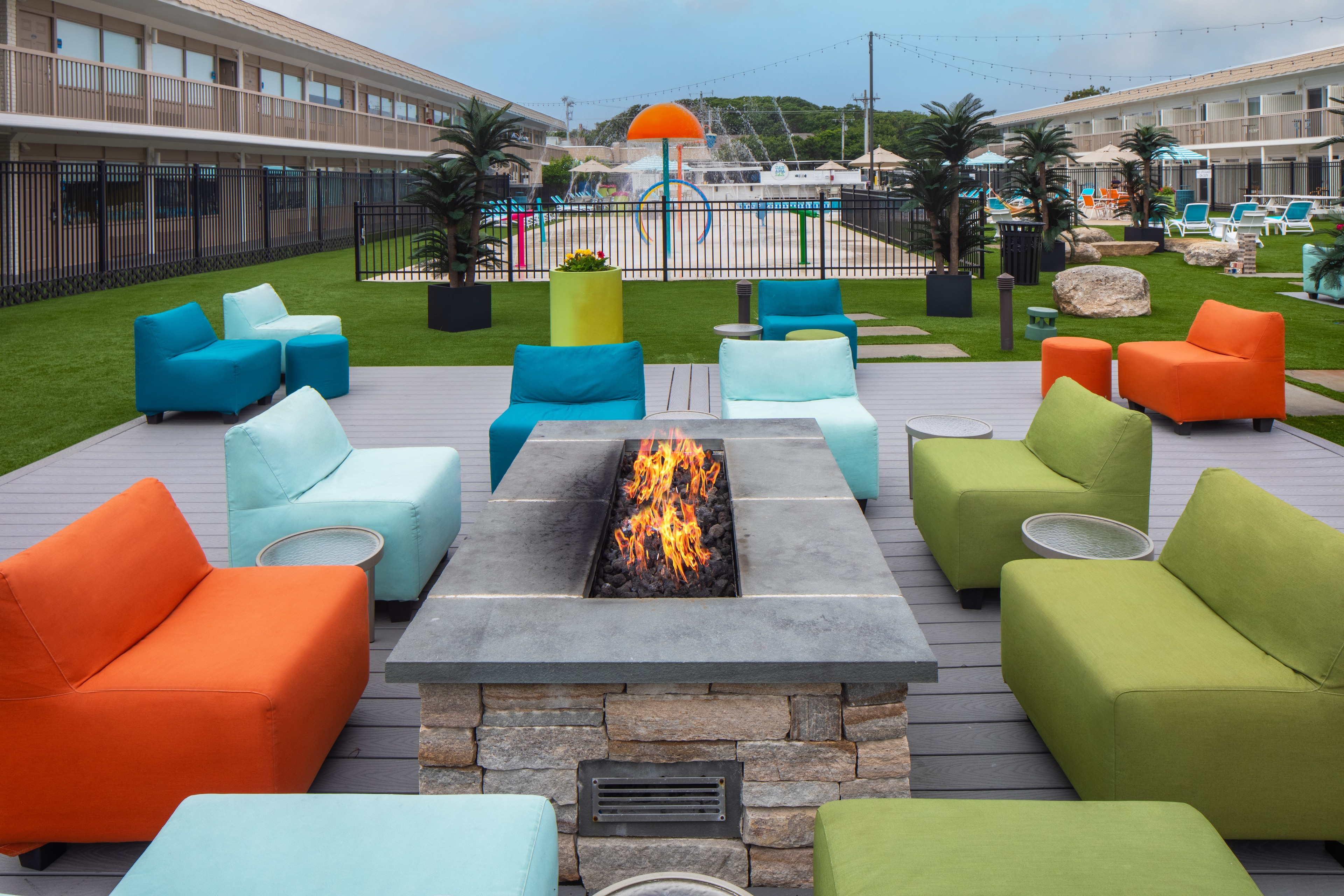 A fire pit with colorful chairs and sofas around it on a deck.