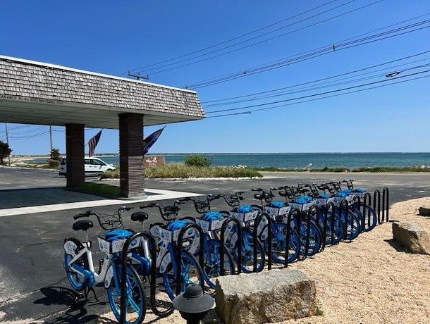 A row of blue and white bicycles parked in a rack outside a building with an ocean view.