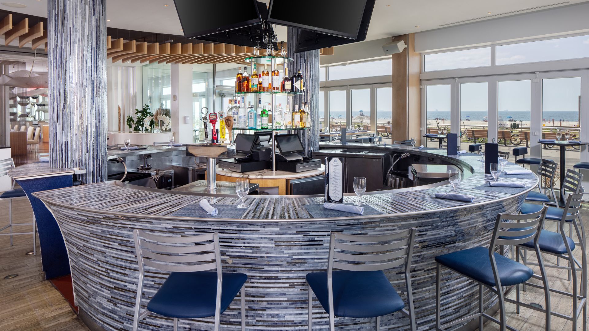 Modern upscale bar with blue chairs and ocean views at The Allegria Hotel, New York