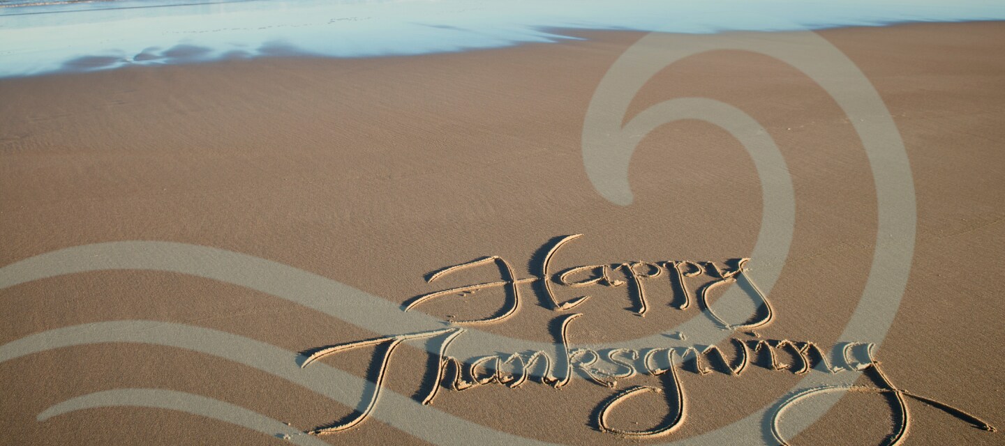 Happy Thanksgiving written in the sand on the beach
