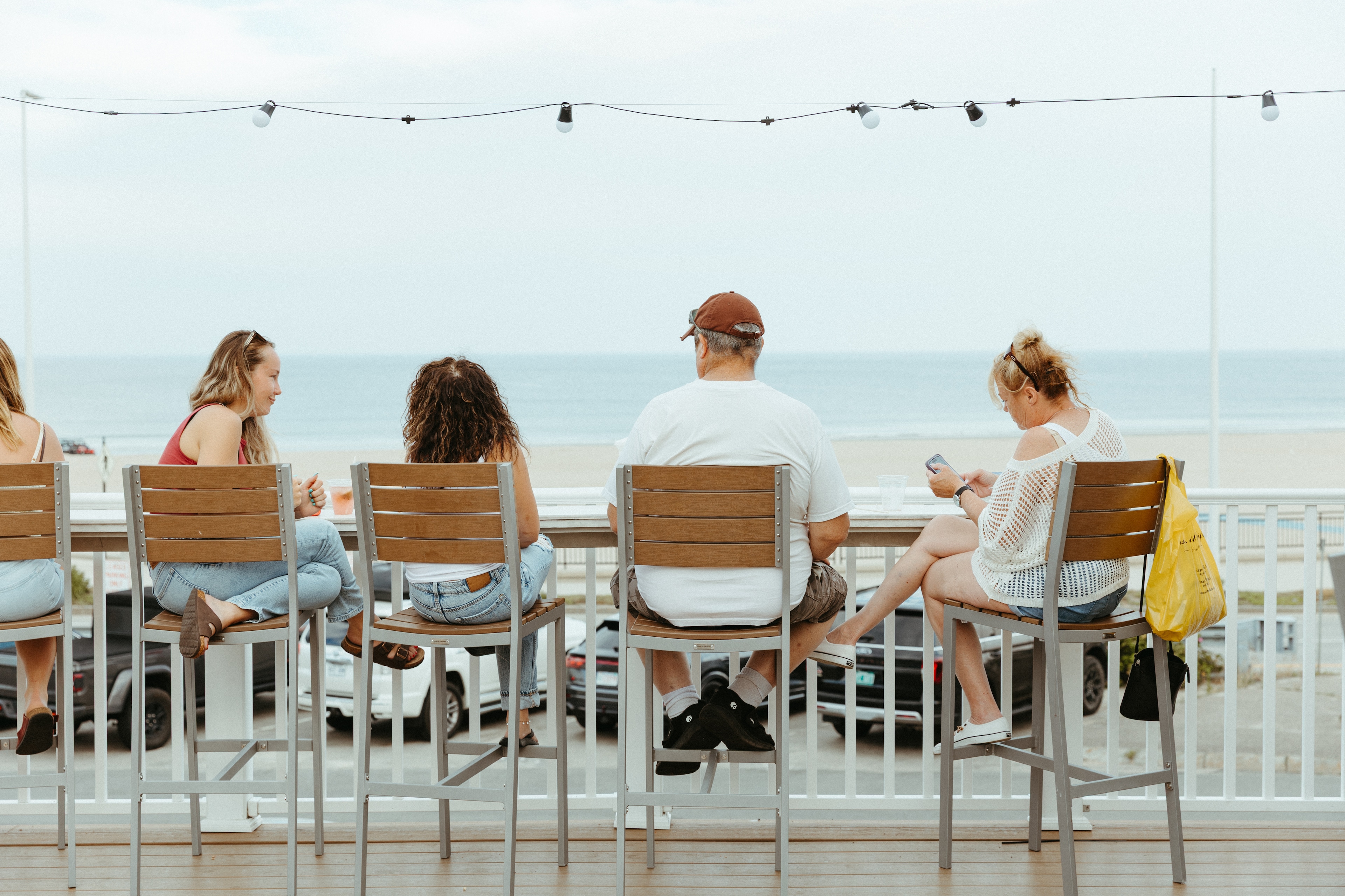 A group of people sitting at a bar with a seaside view