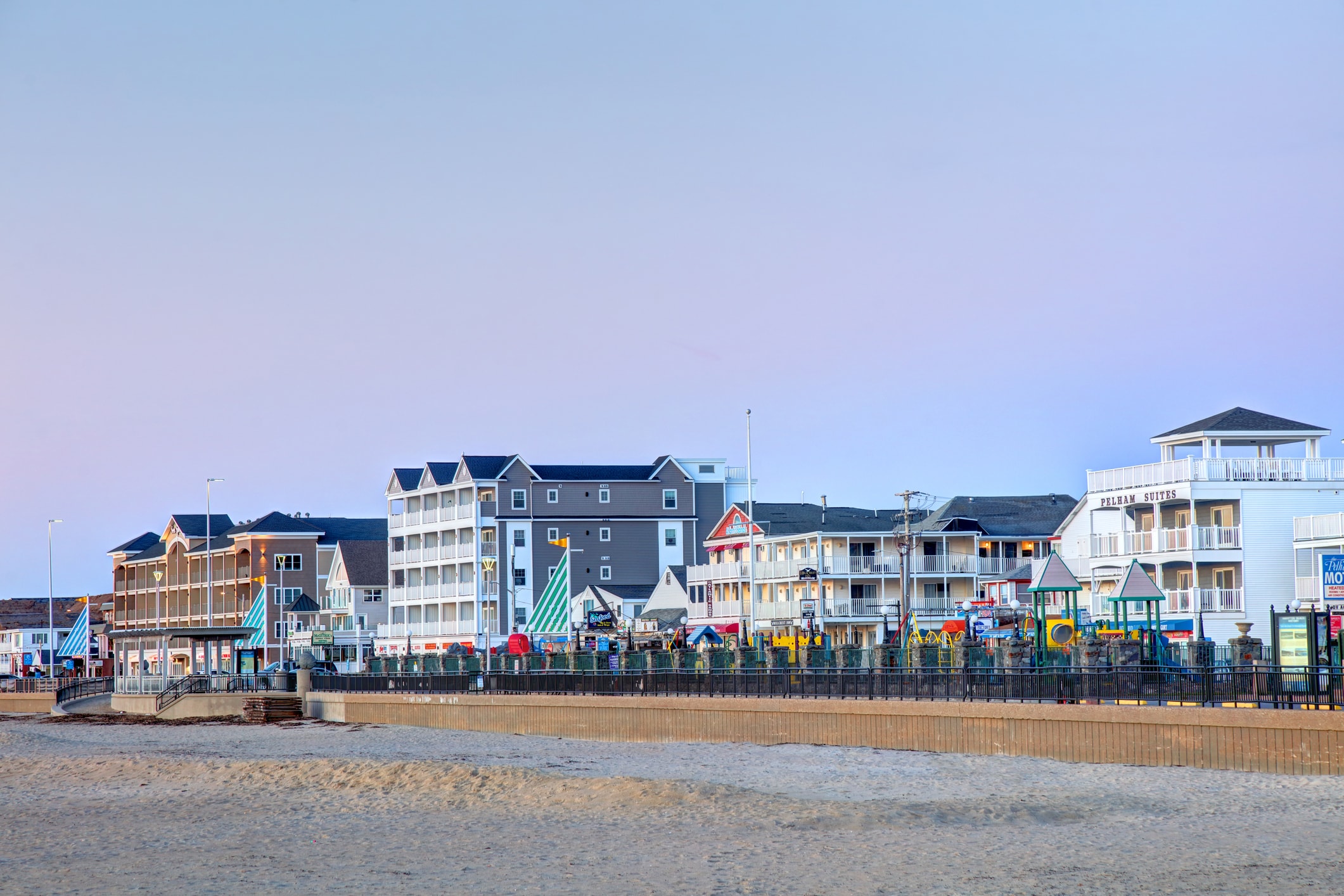 A wide view of a beachfront property with multiple buildings, balconies, and a playground.