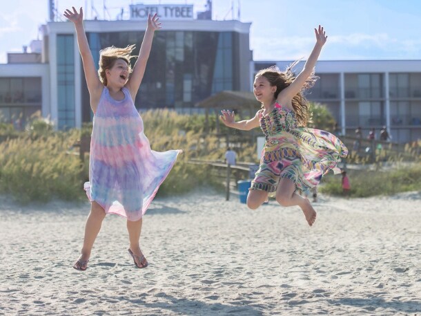 Two girls jumping on the beach in front of Hotel Tybee