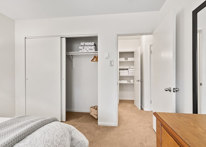 A bedroom with a bed, dresser and closet at California Apartments in Absecon, New Jersey