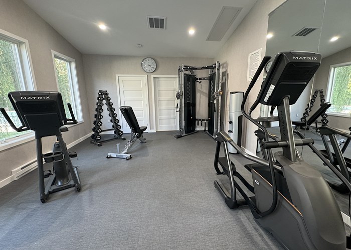 A gym room with exercise equipment and mirrors at California Apartments in Absecon, New Jersey