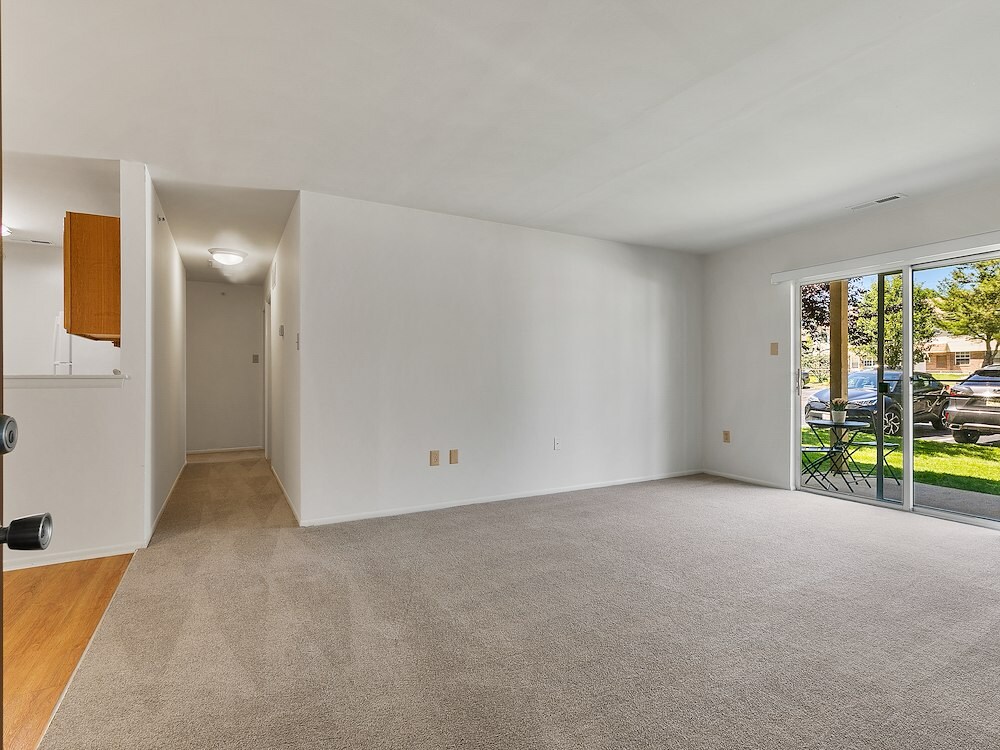 Spacious one-bedroom living room at California Apartments featuring sliding-glass doors that lead to a private patio or balcony.